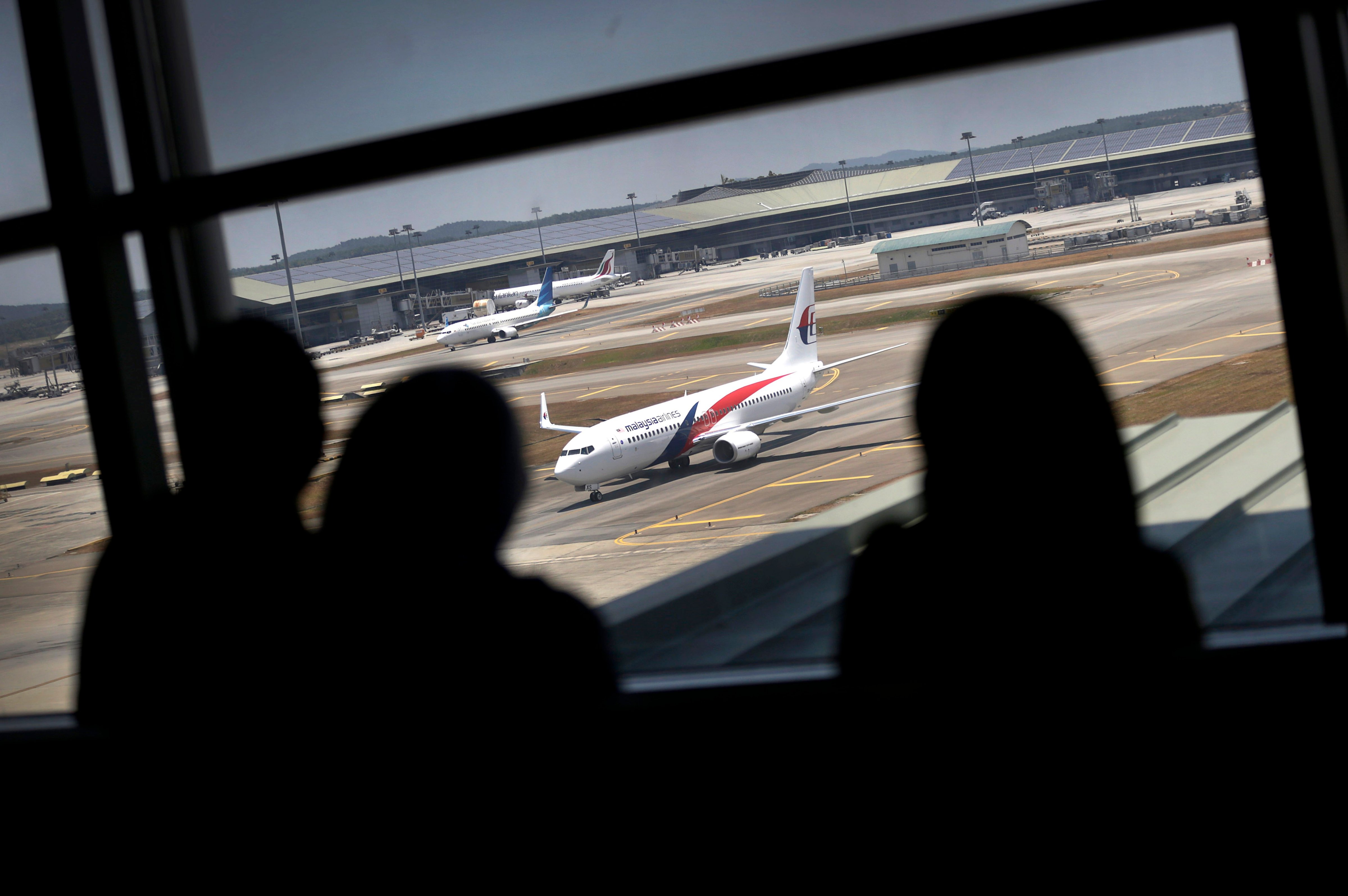 Women are silhouetted as they watch a Malaysia Airlines jet taxi on the tarmac at the Kuala Lumpur International Airport, March 11, 2014, in Sepang, Malaysia. (Wong Maye-E—AP)