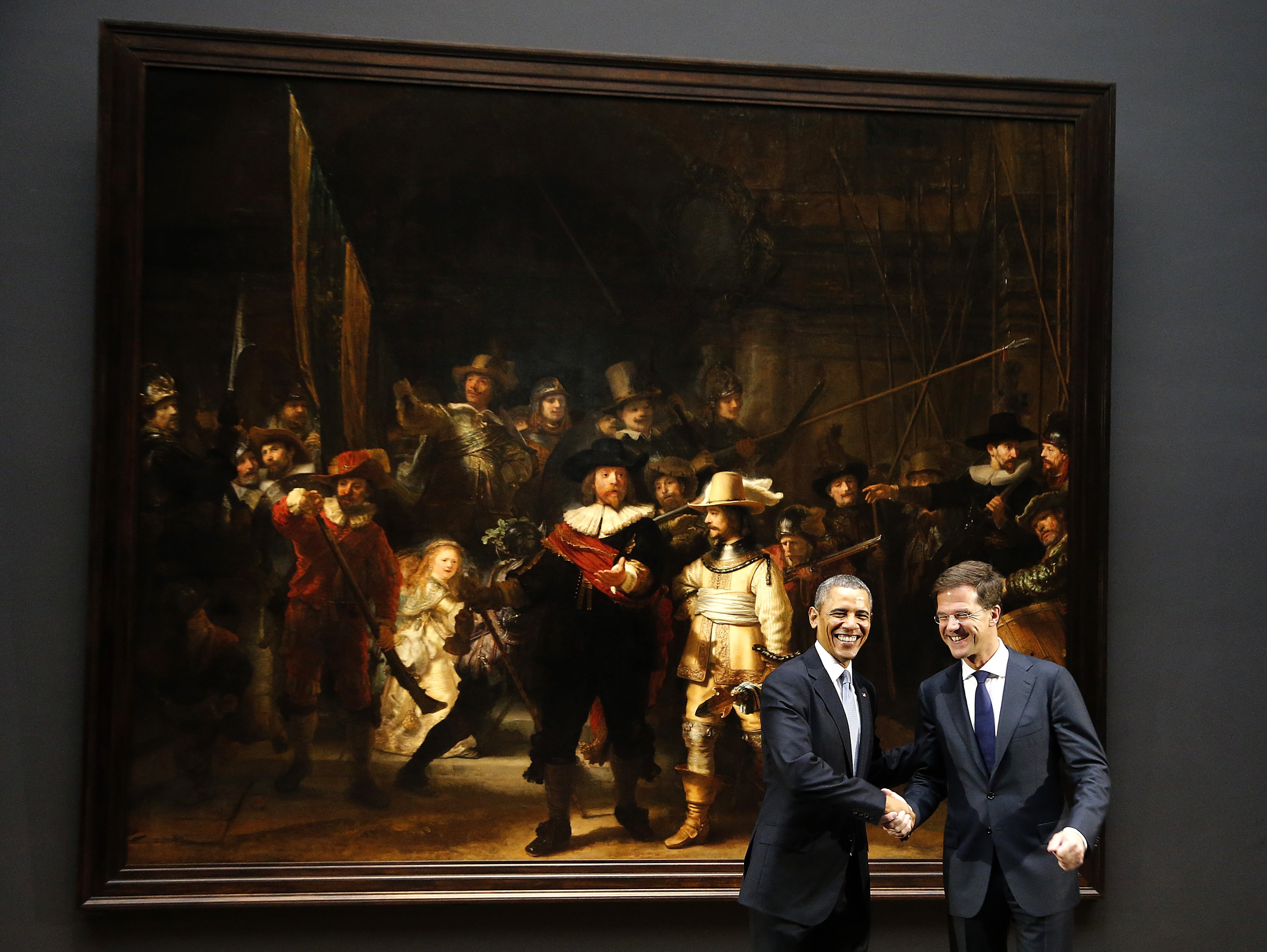 U.S. President Barack Obama, left, shakes hands with Dutch Prime Minister Mark Rutte, right, in front of  Dutch master Rembrandt's The Night Watch painting during a visit to the Rijksmuseum in Amsterdam, Netherlands, Monday, March 24, 2014.