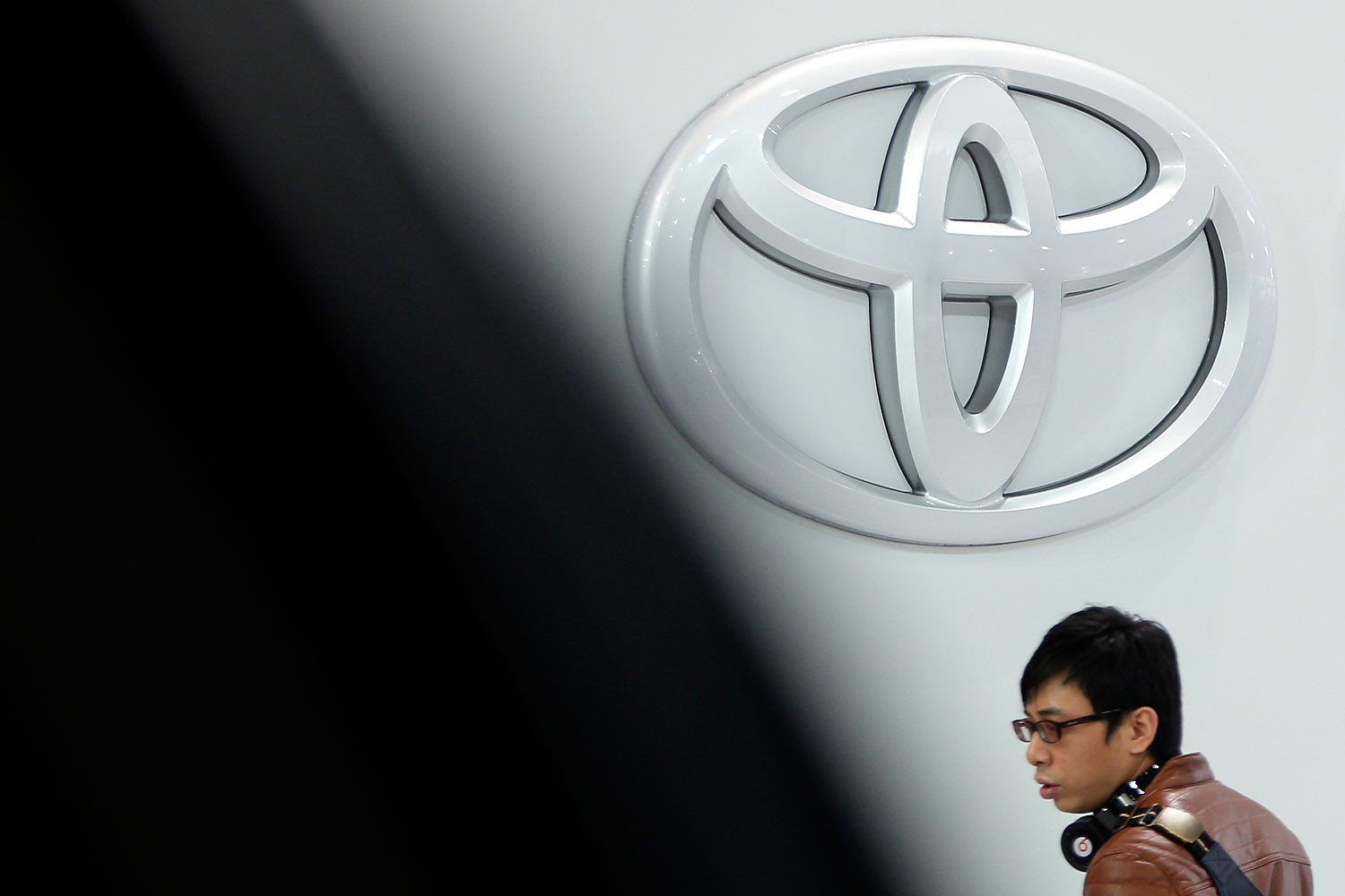 A visitor passes the Toyota Motor Corp. logo on display at the company's showroom in Tokyo, Japan, Feb. 12, 2014.