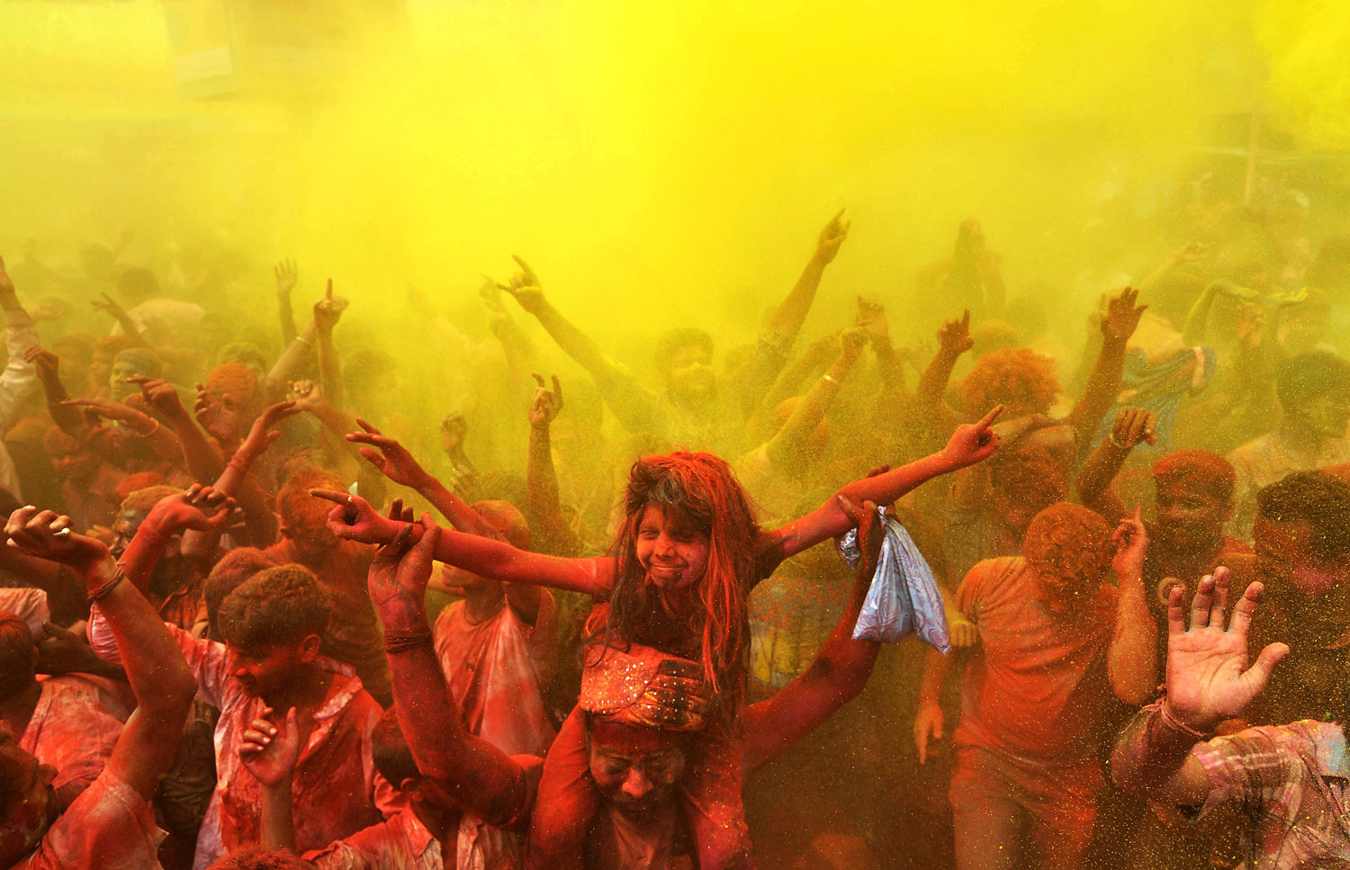 Indian revellers cover each other with coloured powder and dance while taking part in Holi festival celebrations in Guwahati on March 17, 2014.
