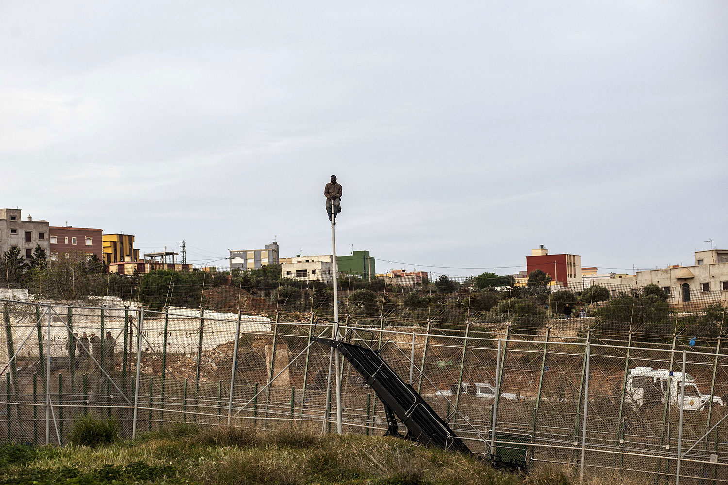 A would-be immigrant waits sitted on a mast on the other side of fences near Beni Enza, into the north African Spanish enclave of Melilla on March 28, 2014.