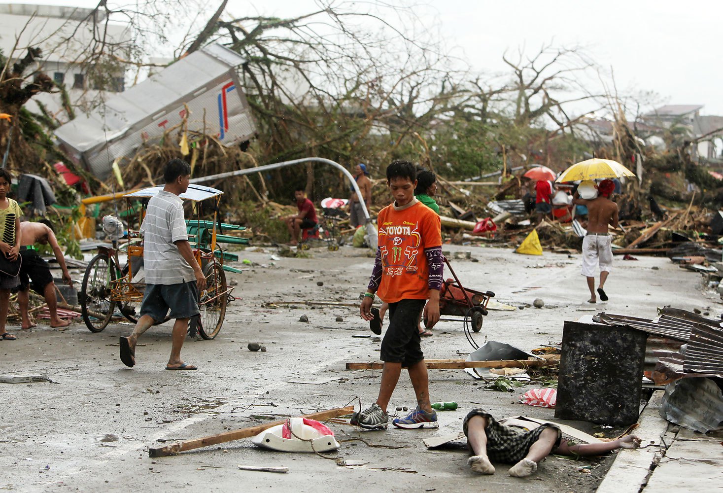 Filipinos walk past a victim left on the side of a street in the typhoon-devastated city of Tacloban, in the Philippines' Leyte province, on Nov. 9, 2013