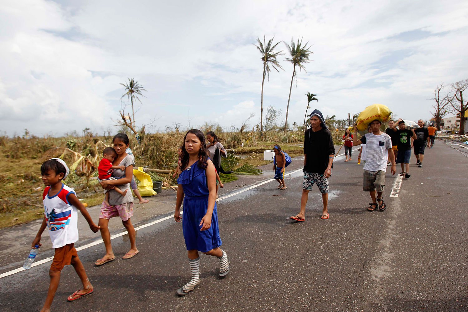 Survivors walk past a damaged town on Nov. 9, 2013, after strong winds brought by Supertyphoon Haiyan battered Tacloban, in central Philippines