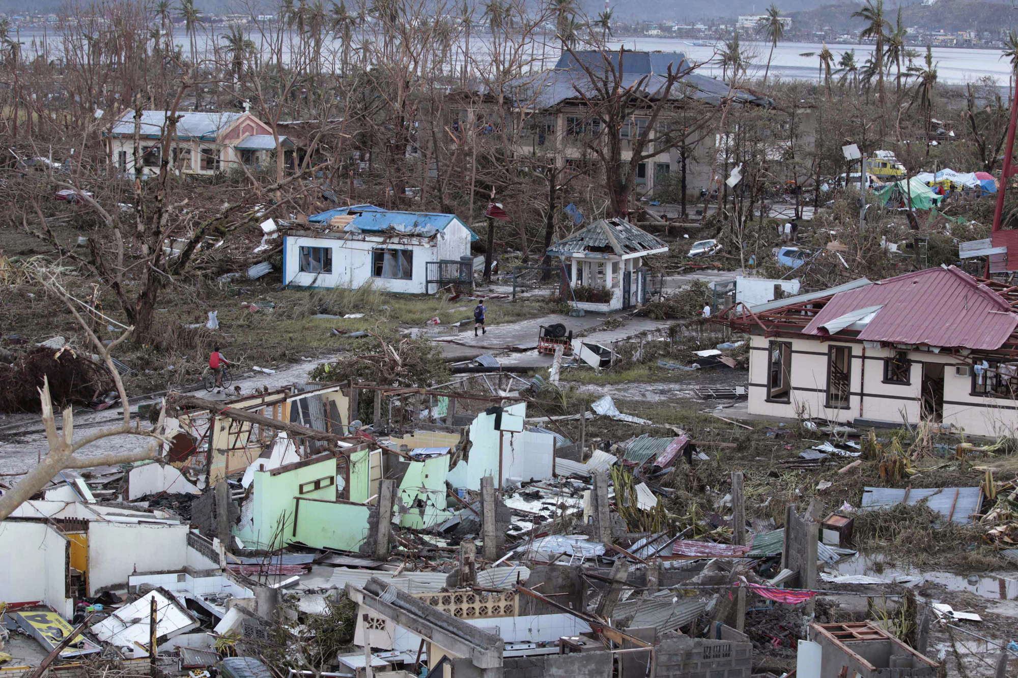A resident walks by remains of houses on Nov. 9, 2013, after Supertyphoon Haiyan slammed into Tacloban, in the Philippines' Leyte province