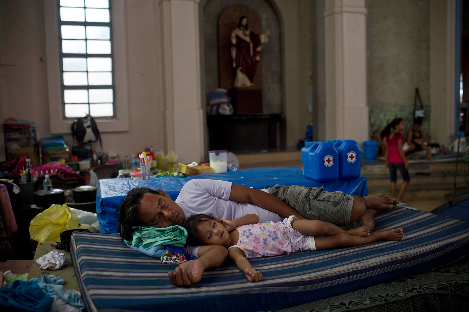 A man and his child sleep inside a Catholic Cathedral where they and other Typhoon Haiyan survivors are taking shelter in Tacloban, Philippines on November 22, 2013.