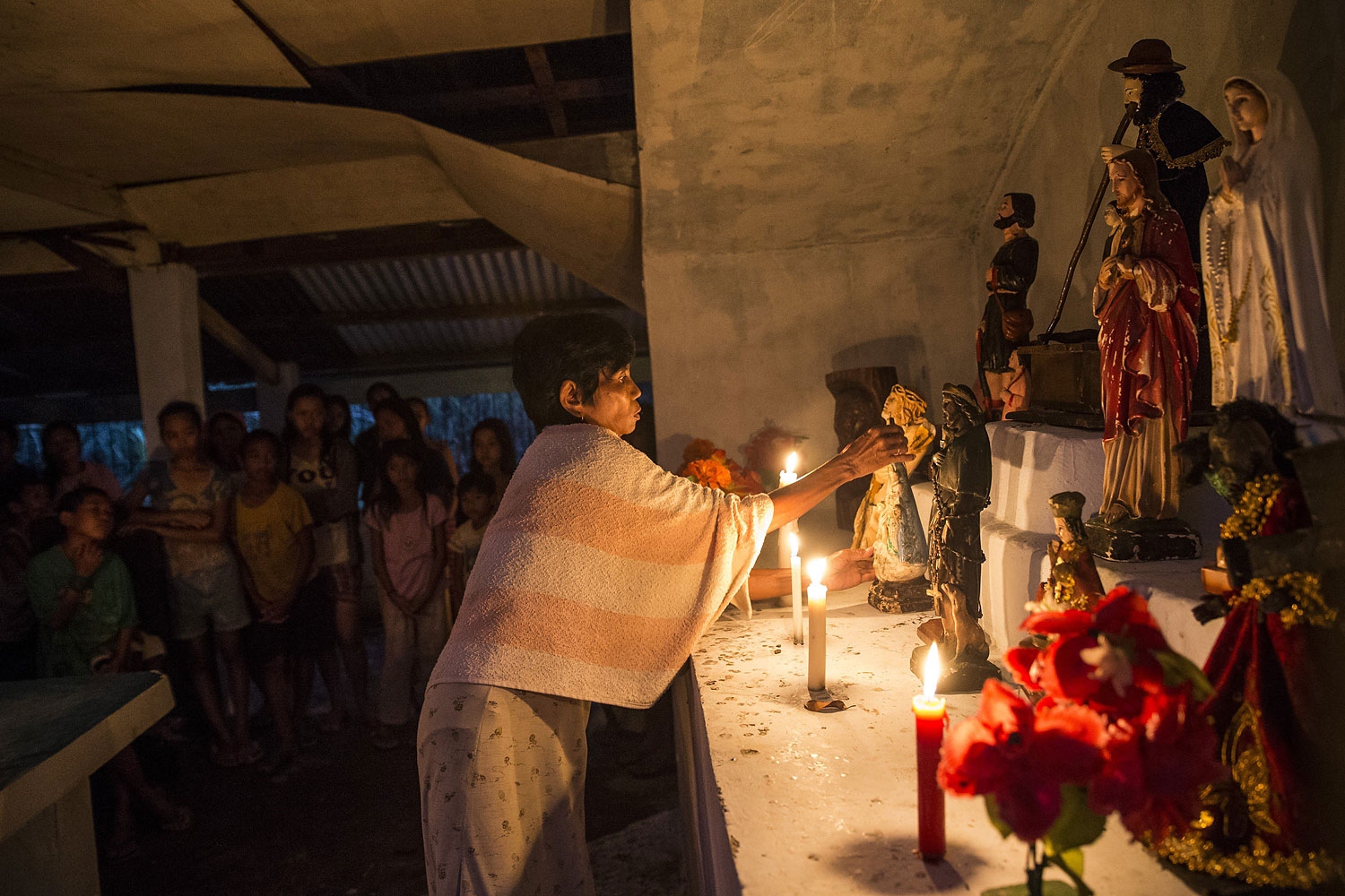 A woman arranges religious statues during a Latin mass ceremony at a local Chapel in Santa Rita township on November 22, 2013 in Eastern Samar, Philippines.
