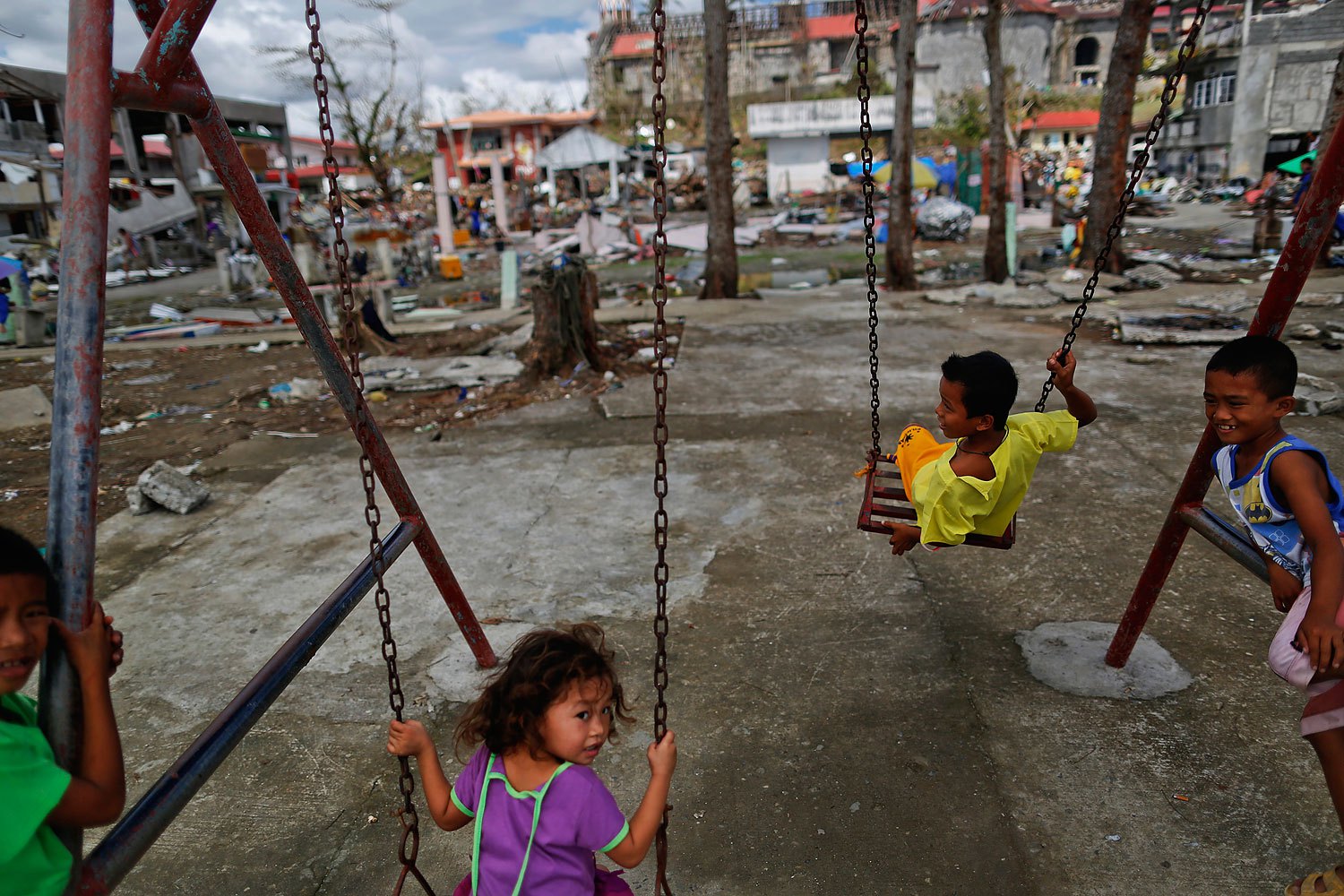 Children, survivors of Typhoon Haiyan, play on swings at a devastated area of Basey, north of Tacloban, November 19, 2013.