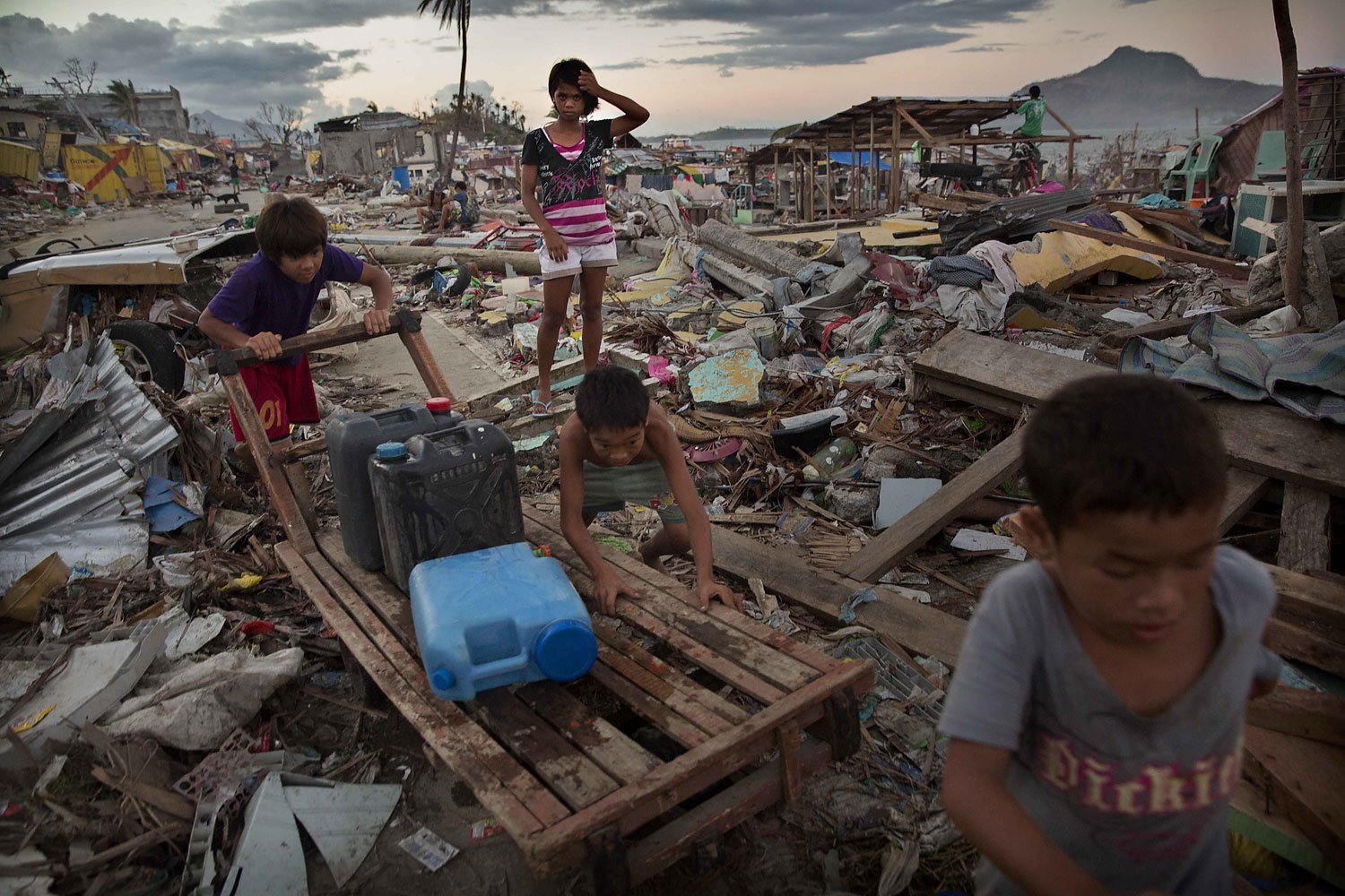Young residents push a cart as they collect water in an area destroyed in the aftermath of Typhoon Haiyan on November 18, 2013 in Tacloban, Philippines.