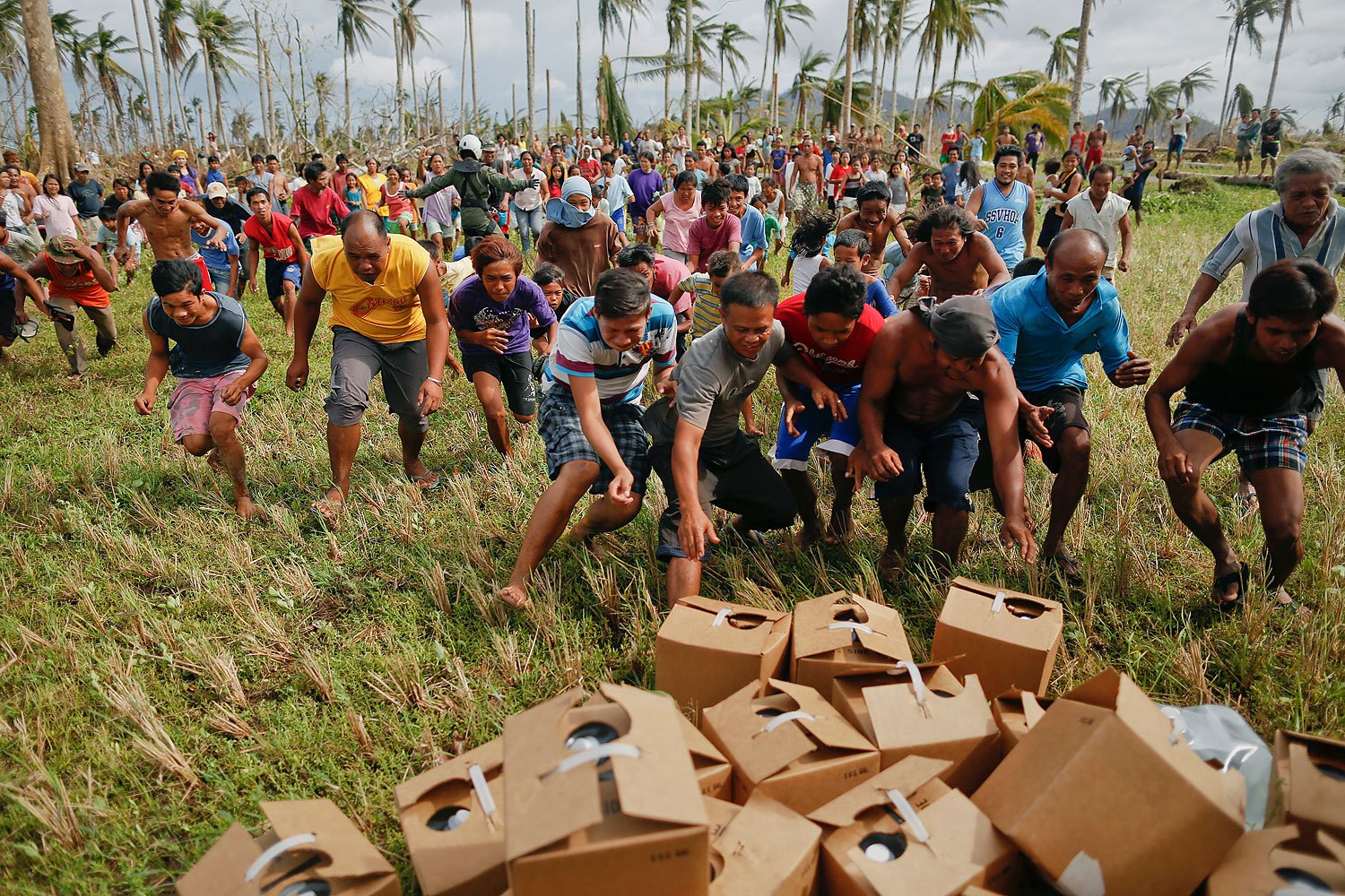 Survivors of Typhoon Haiyan rush to grab fresh water delivered by a U.S. military helicopter to their isolated village north of Tacloban, November 17, 2013.