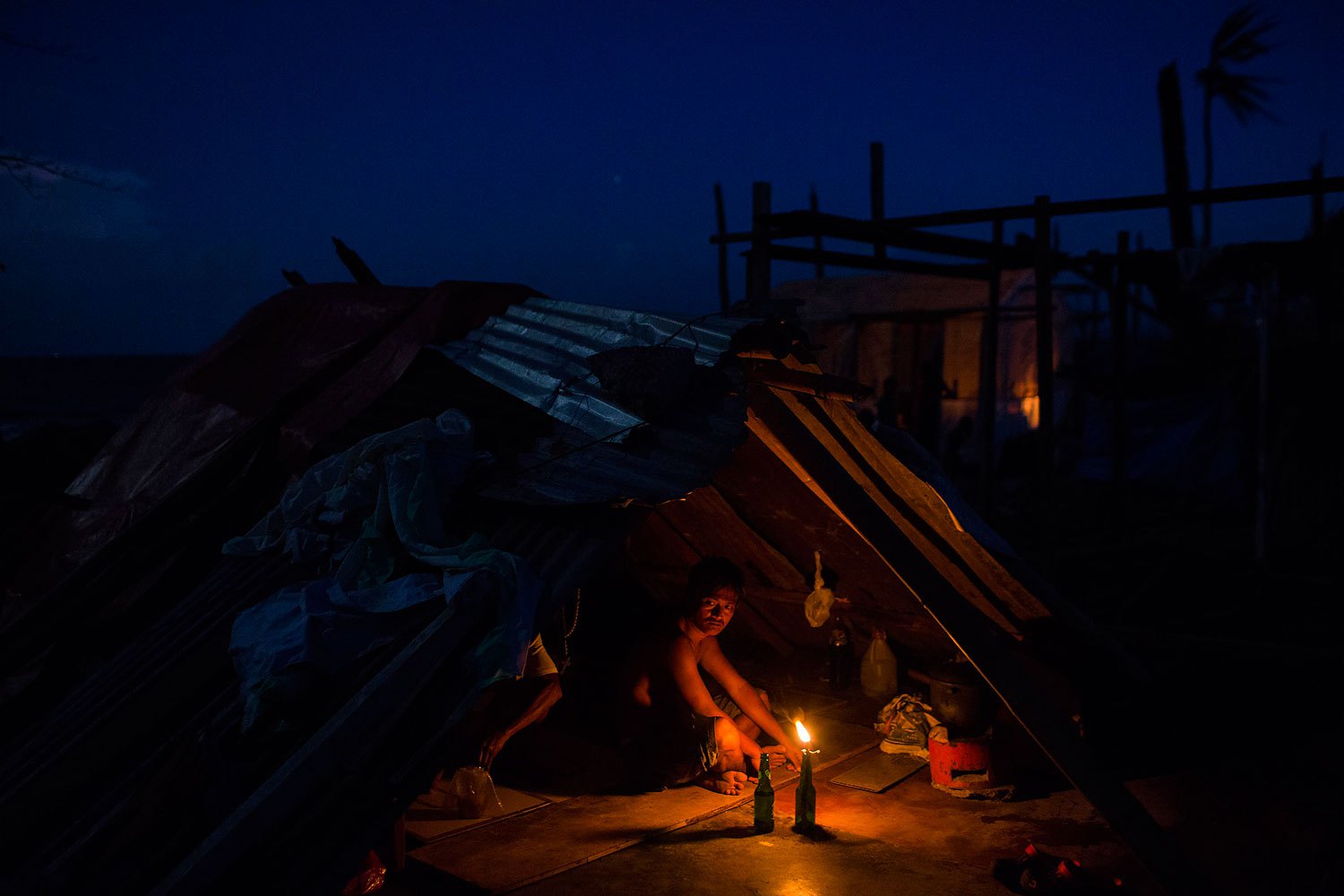 A man who's home was destroyed by Typhoon Haiyan sits by a candle light in the rubble of his home in Tanuan, Philippines on November 15, 2013.