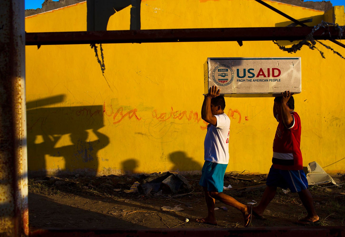 Typhoon Haiyan survivors help carry USAID donated food after a U.S. military helicopter unloaded it in the destroyed town of Guiuan, Philippines on November 14, 2013.