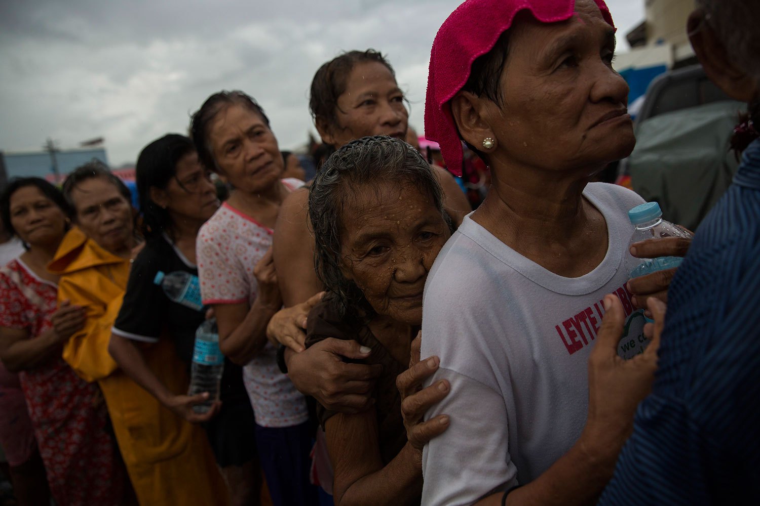 Displaced people effected by Haiyan Typhoon queue in the rain for the first aid delivery at a displacement camp in Tacloban, Philippines on November 14, 2013.