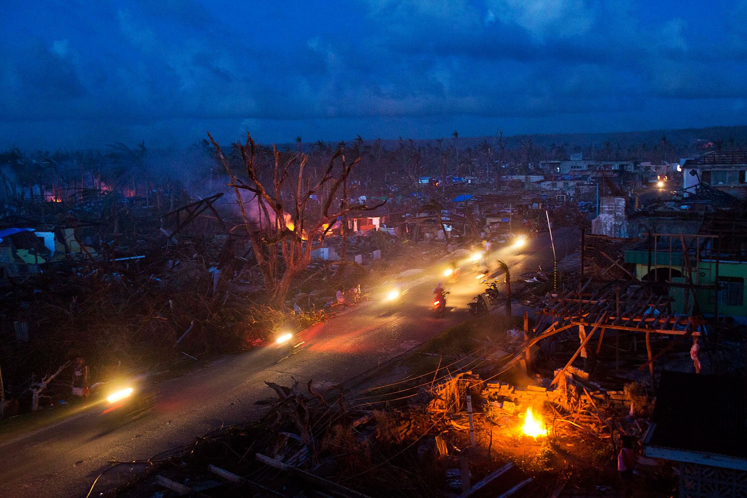 Typhoon Haiyan survivors ride motorbikes through the ruins of the destroyed town of Guiuan, Philippines on November 14, 2013.