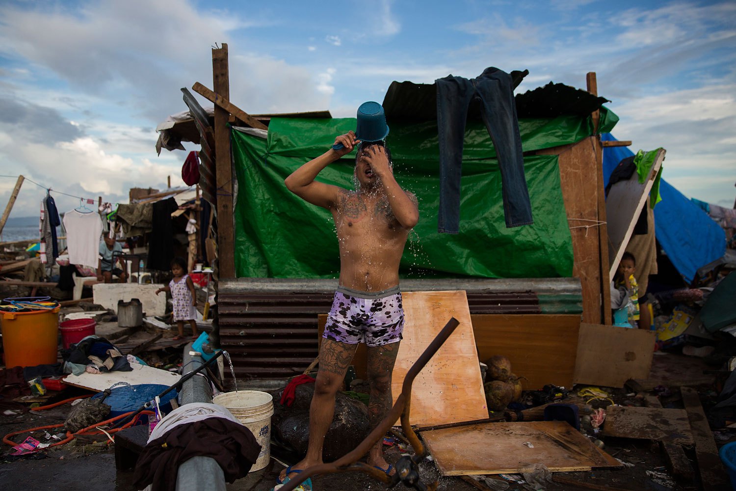 A man washes outside his temporary home on the site of his former home that was destroyed by Haiyan Typhoon in Tacloban, Philippines on November 13, 2013.