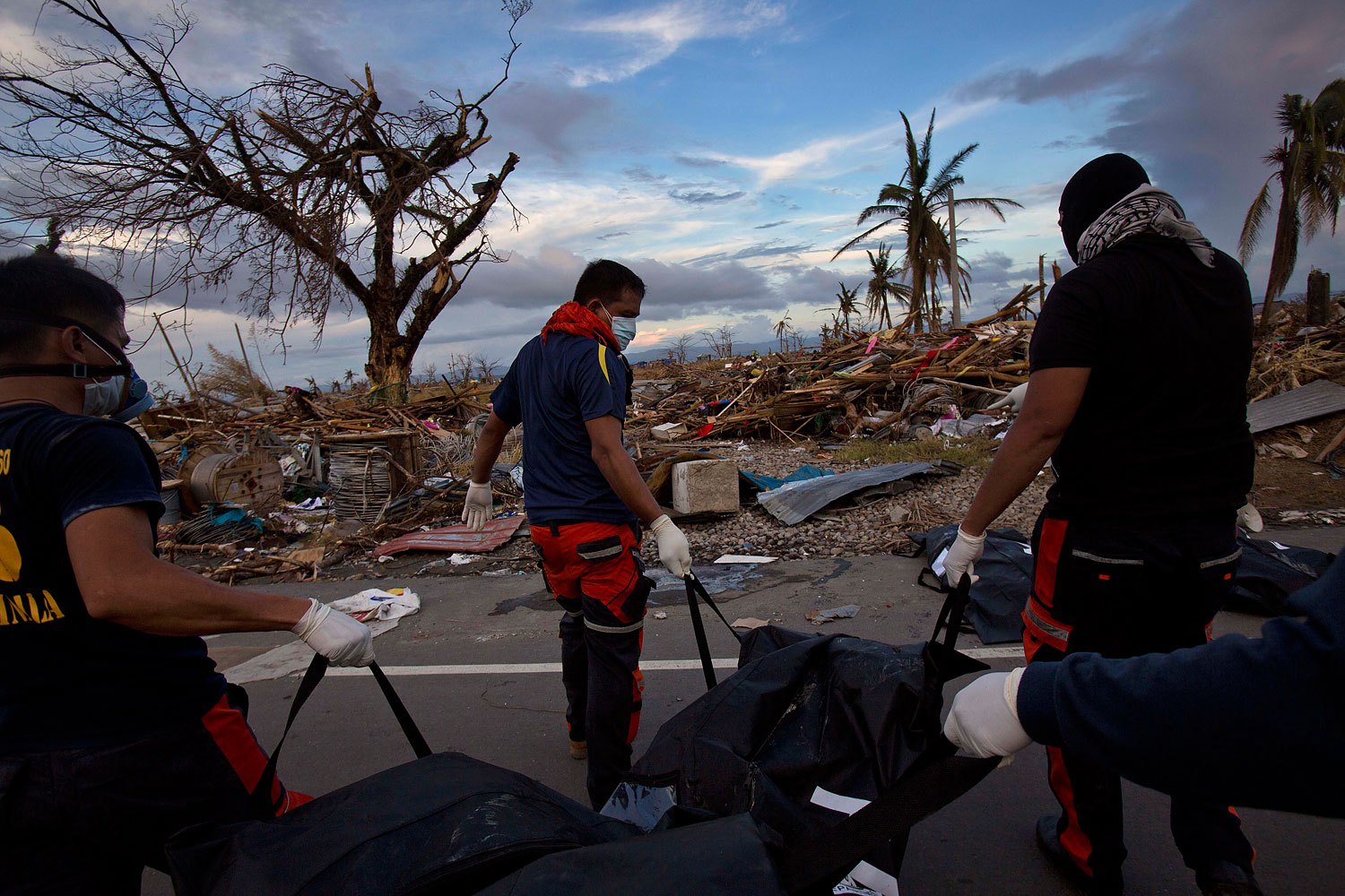 Members of a Philippines rescue team carry corpses in body bags as they search for the dead in the Typhoon Haiyan ravaged city of Tacloban on November 13, 2013.