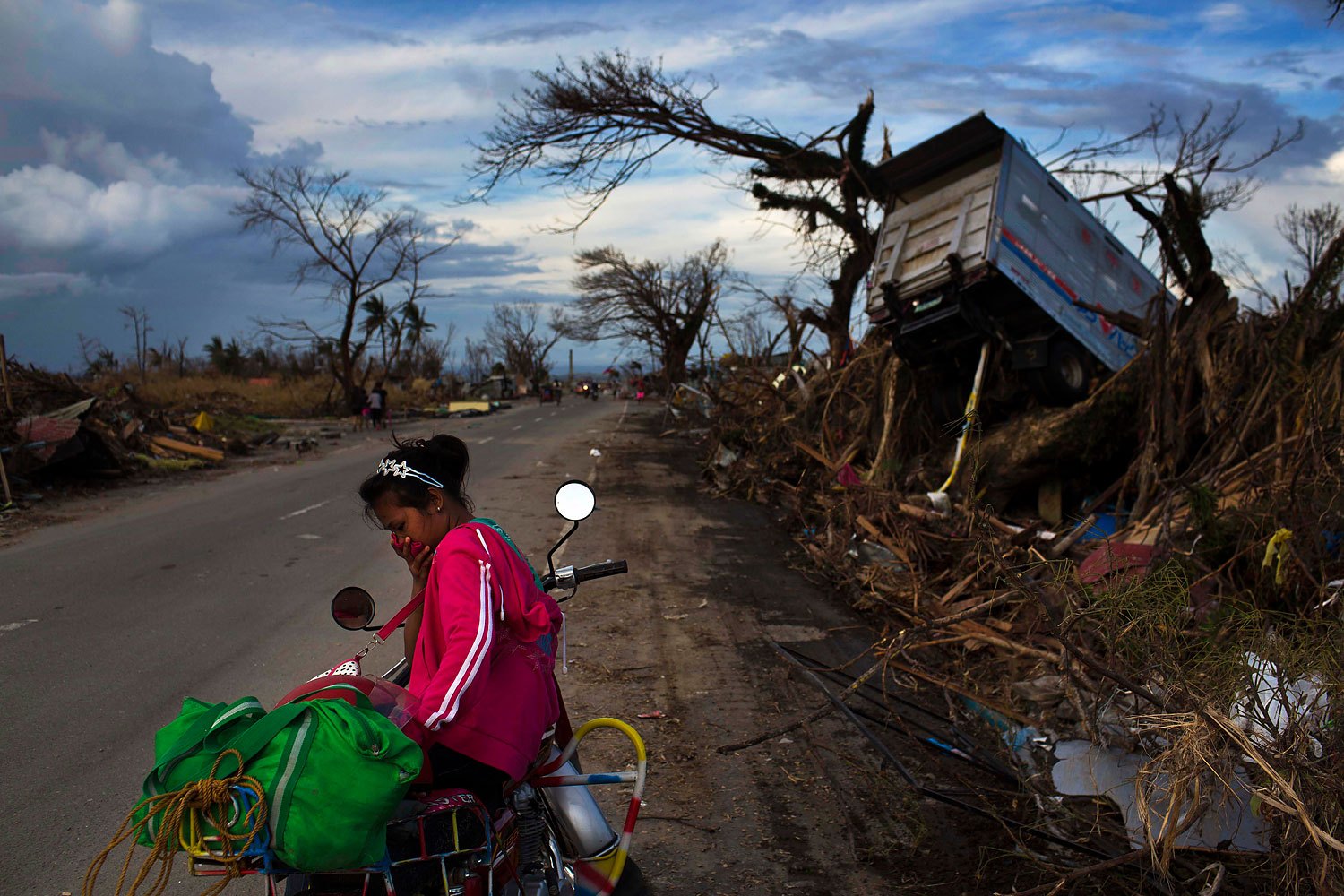A woman rests on a roadside with her family's belongings near the Typhoon Haiyan ravaged town of Tacloban, Philippines on November 13, 2013.