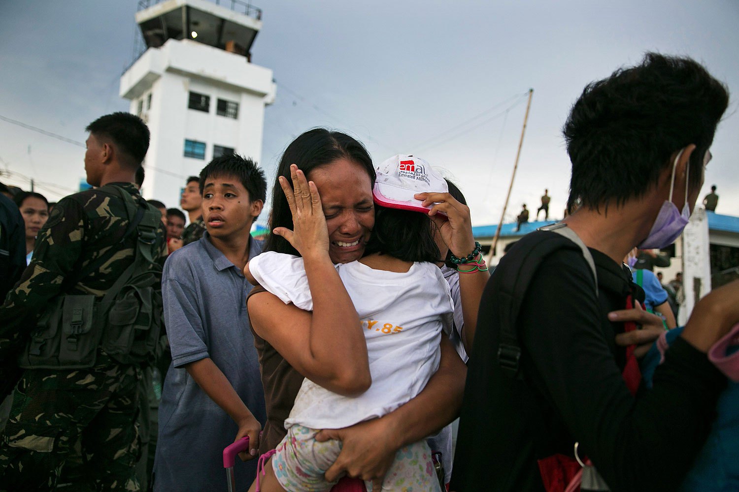 A woman carrying a child cries as they and other survivors of Supertyphoon Haiyan wait to board an aircraft during an evacuation in the Philippine town of Tacloban on Nov. 12, 2013