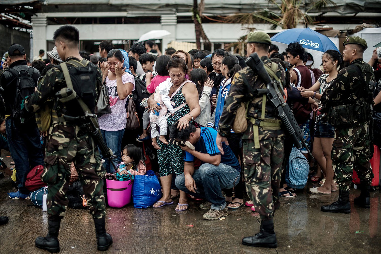 A woman holding a baby comforts a crying relative as a plane leaves the airport during evacuation operations in Tacloban, on the eastern island of Leyte on November 12, 2013 after Super Typhoon Haiyan swept over the Philippines.