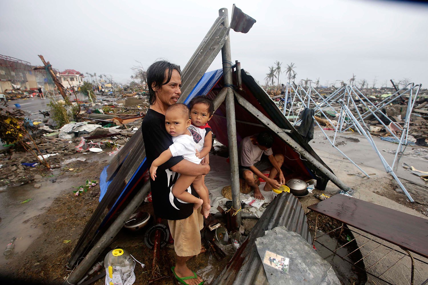 A Filipino father and his children wait for food relief outside their makeshift tent in the supertyphoon-devastated city of Tacloban, in the Philippines' Leyte province, on Nov. 10, 2013