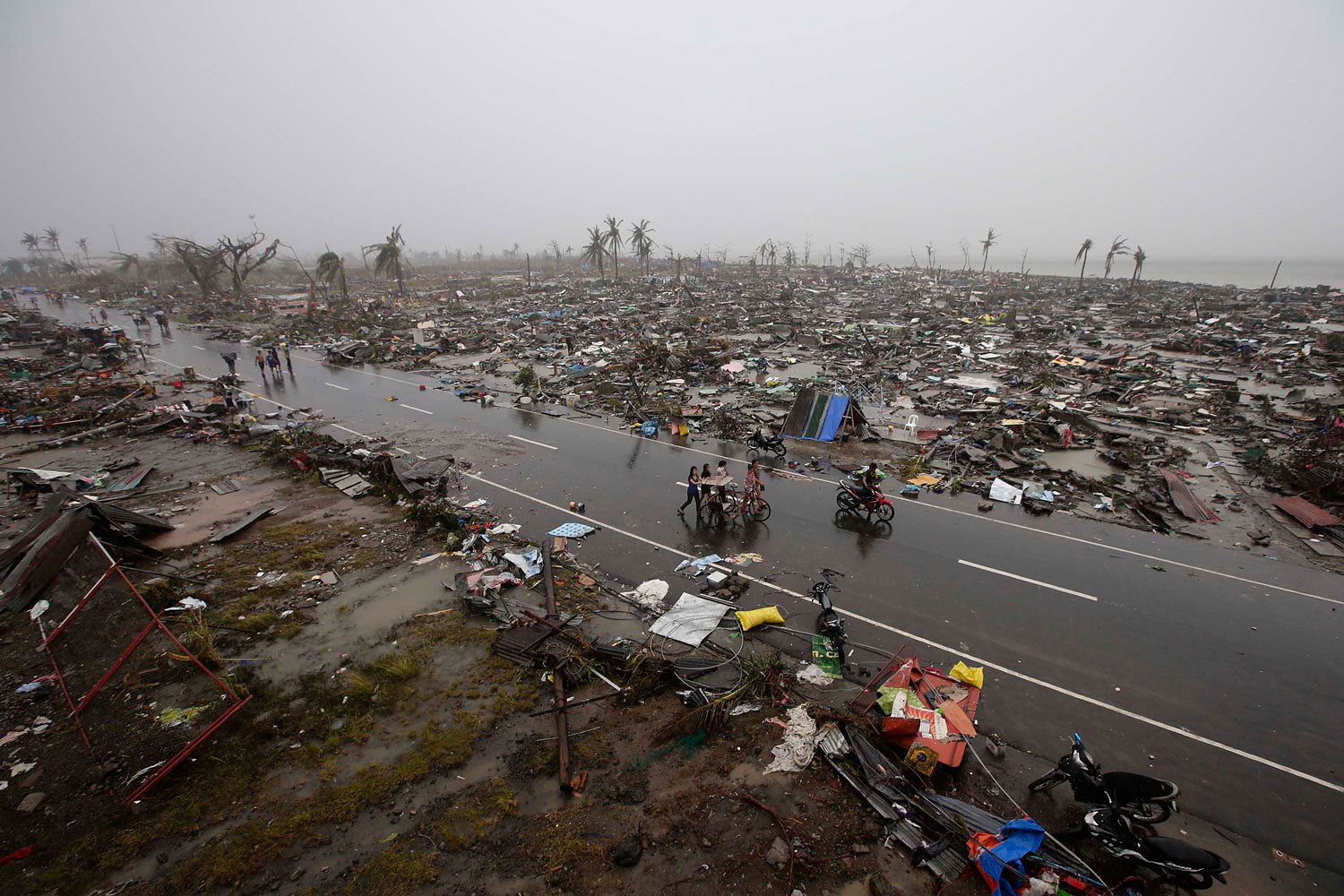 Filipino villagers carrying their belongings during a heavy downpour walk past rubble of houses in the supertyphoon-devastated city of Tacloban, in the Philippines' Leyte province, on Nov. 10, 2013