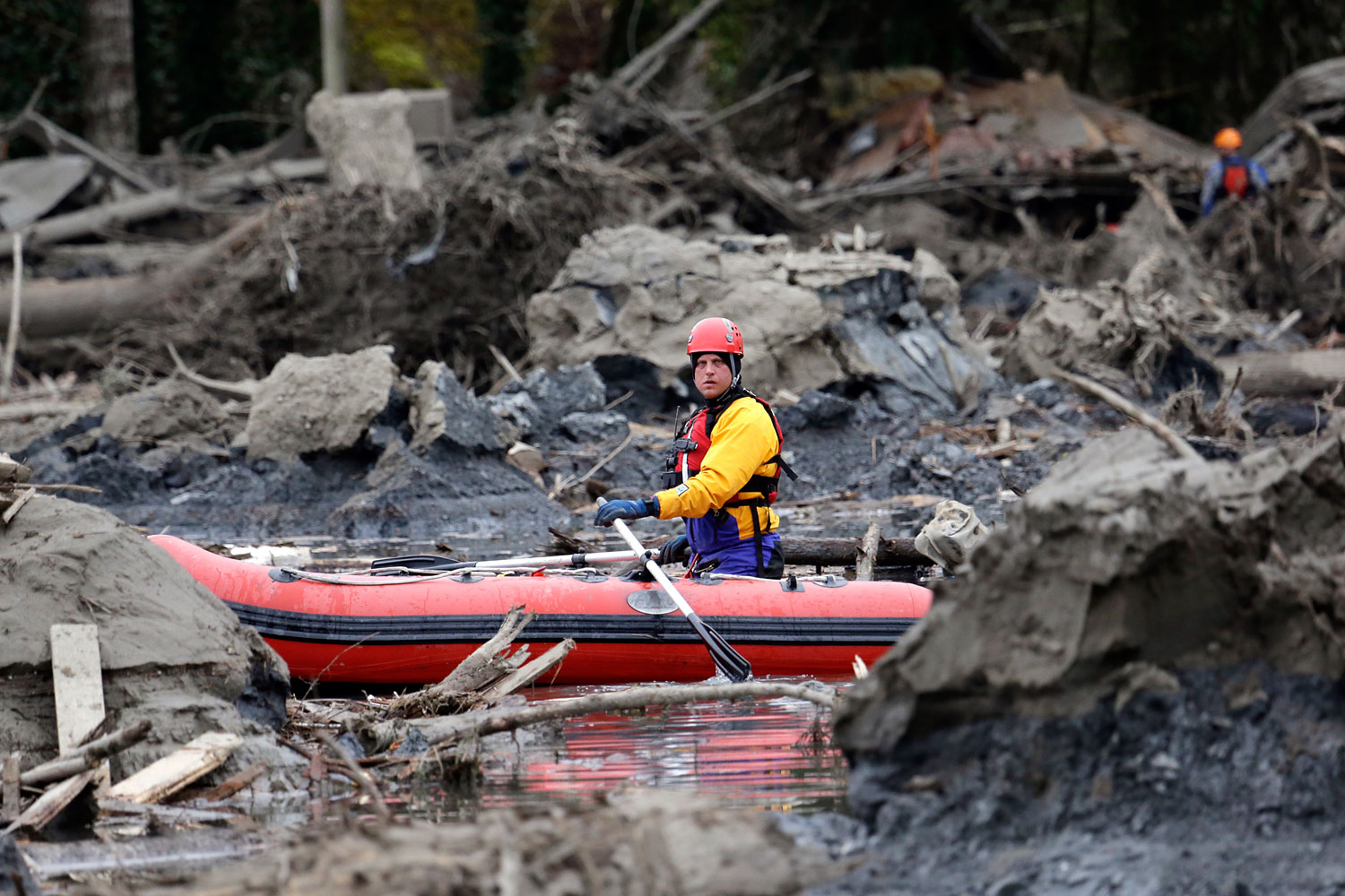A searcher uses a small boat to look through debris from a deadly mudslide, March 25, 2014, in Oso, Wash.
