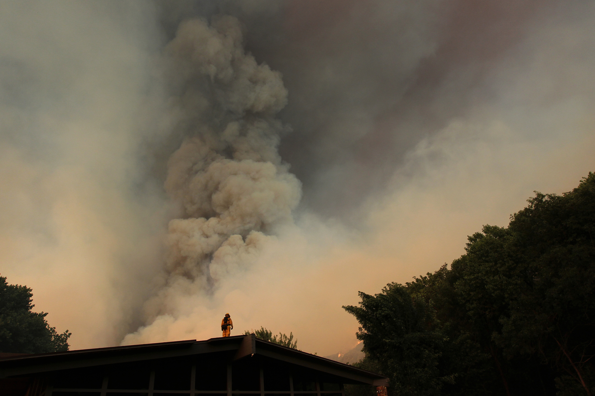 A firefighter watches from a rooftop as the Powerhouse fire closes in around the Canyon Creek Complex sports camp during a fast run toward Lake Hughes on June 1, 2013 south of Lake Hughes, Calif. The 19,500-acre wildfire destroyed numerous homes overnight.