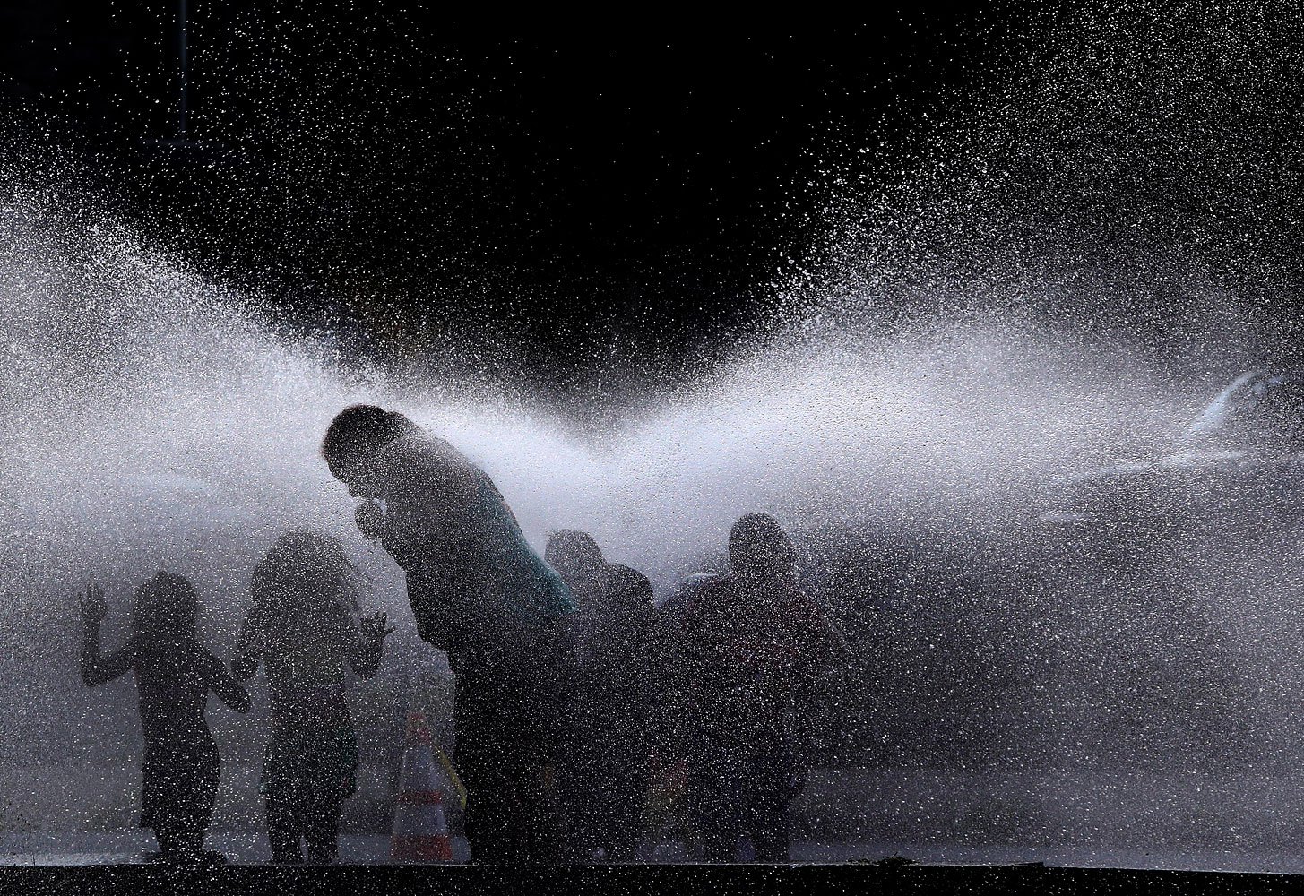 People cool off in the spray of an open hydrant on a hot evening in Lawrence, Mass., July 16, 2013. Americans across the northeast and midwest tried to keep their cool after several consecutive 90-degree days.