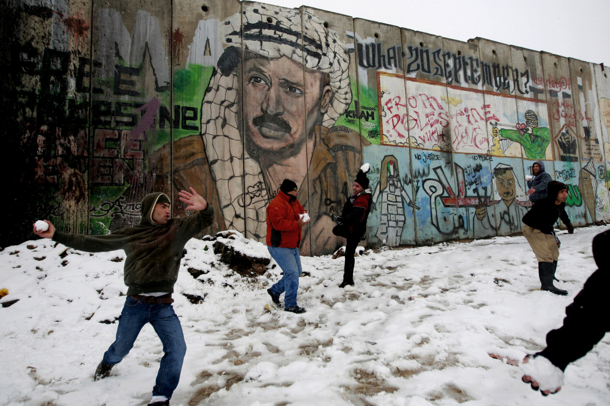 Palestinians play in the snow next to a section of Israel's separation barrier in Qalandia between Jerusalem and the West bank city of Ramallah, Jan. 10, 2013. The storm was the biggest of its kind to hit the region in 30 years.