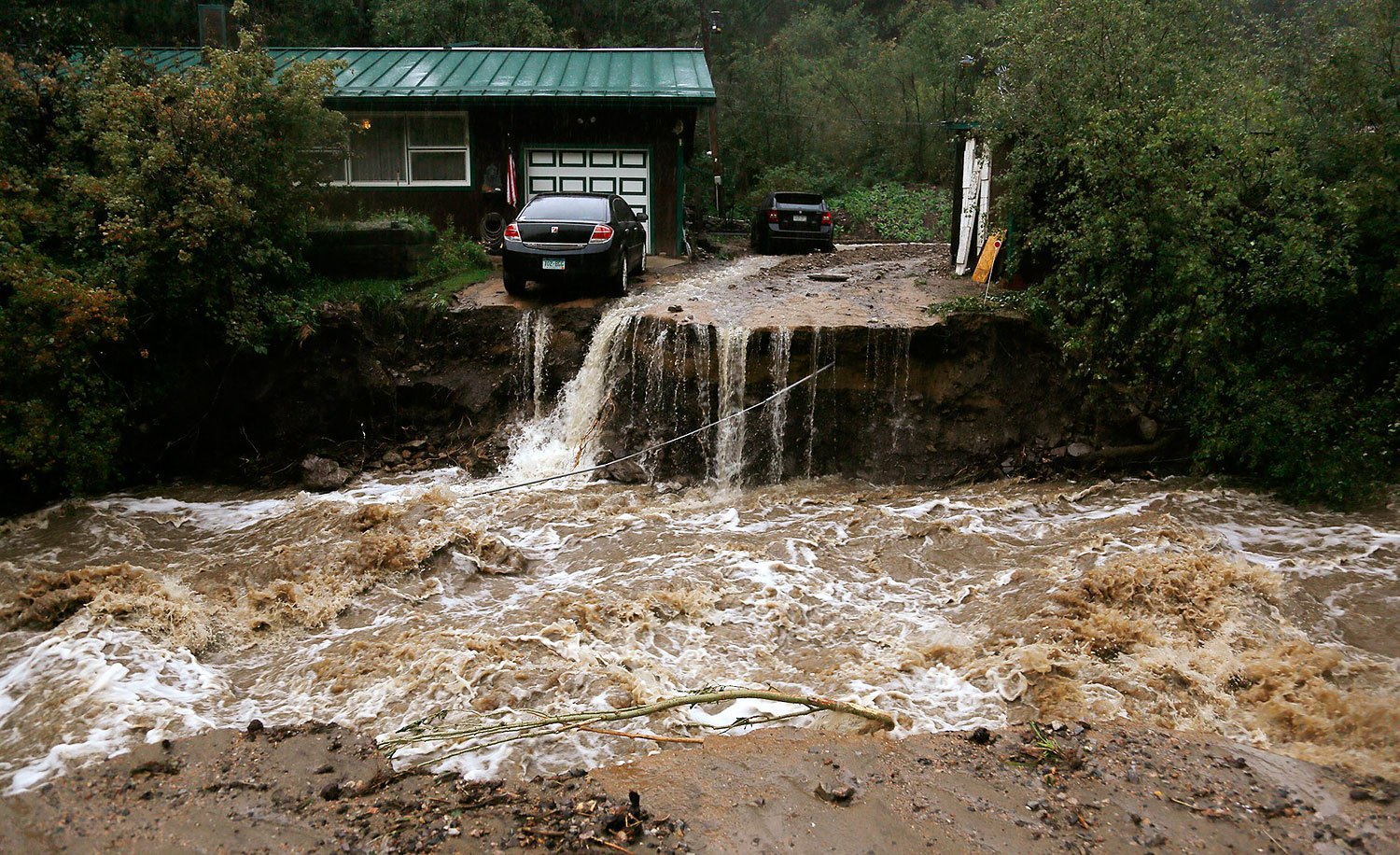 A home and car are stranded after a flash flood in Coal Creek destroyed the bridge near Golden, Colorado Sept. 12, 2013. Flooding in Colorado left eight people dead, prompted hundreds to be evacuated, caused building collapses and stranded cars, officials said.