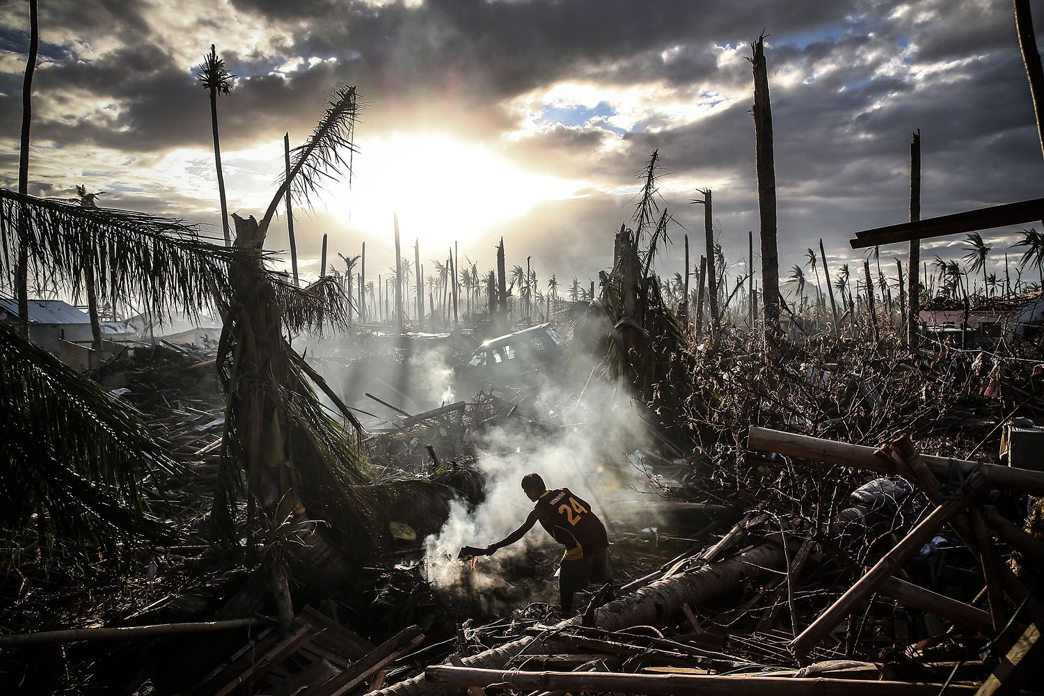 A man fans flames on a fire in Tanauan, Leyte province, Philippines, on November 19, 2013. Typhoon Haiyan devastated the nation leaving at least 6,000 dead.