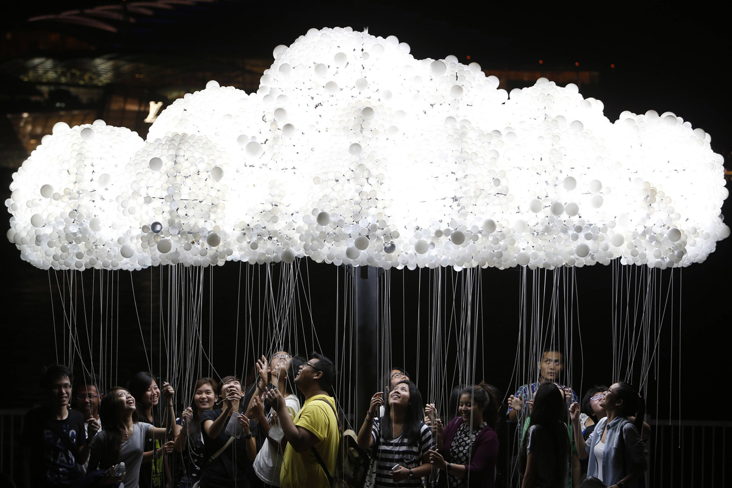 A group of people pose for pictures with light installation "CLOUD" in Singapore