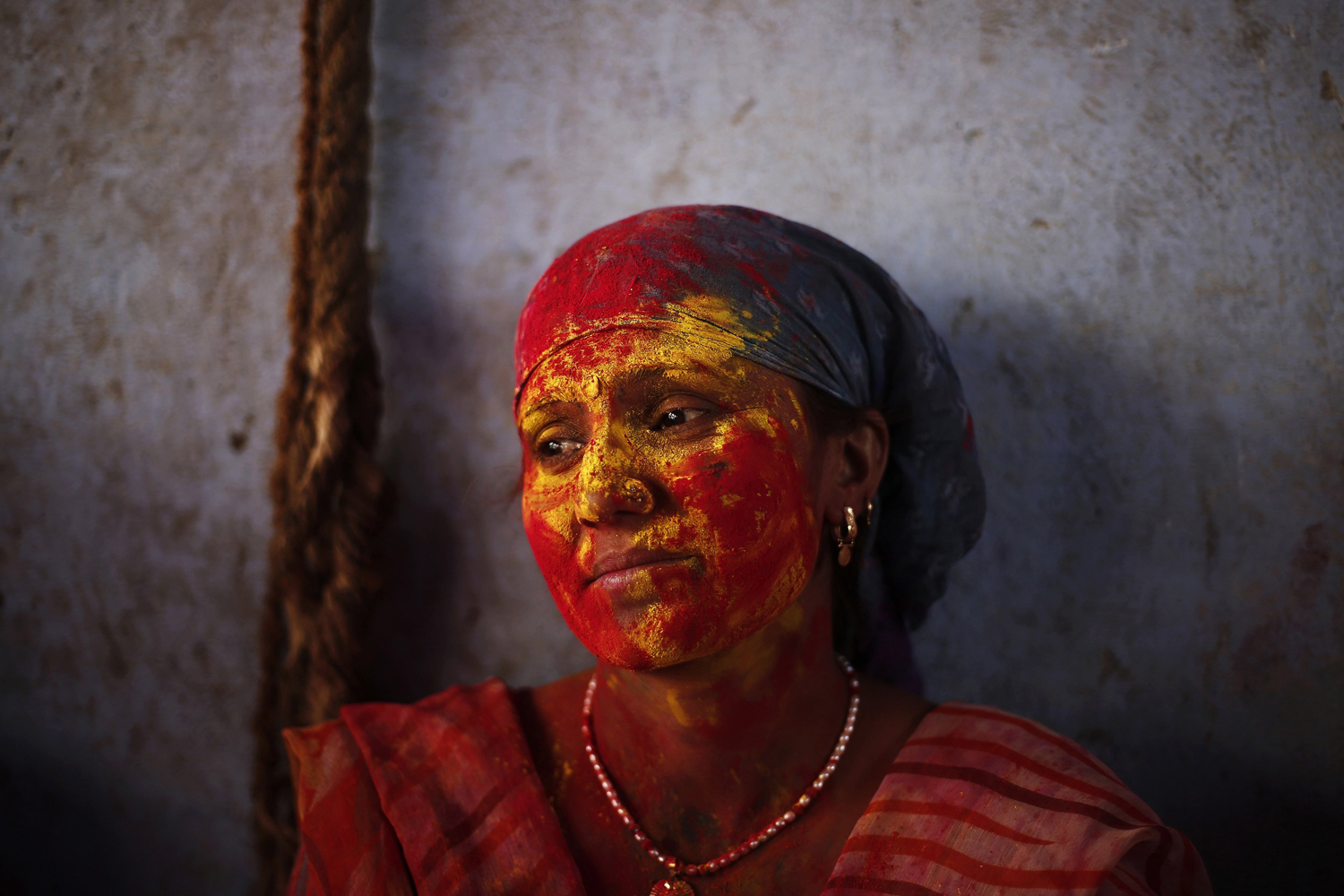 A Hindu woman is seen covered with coloured powder at a temple during "Lathmar Holi" at Nandgaon village