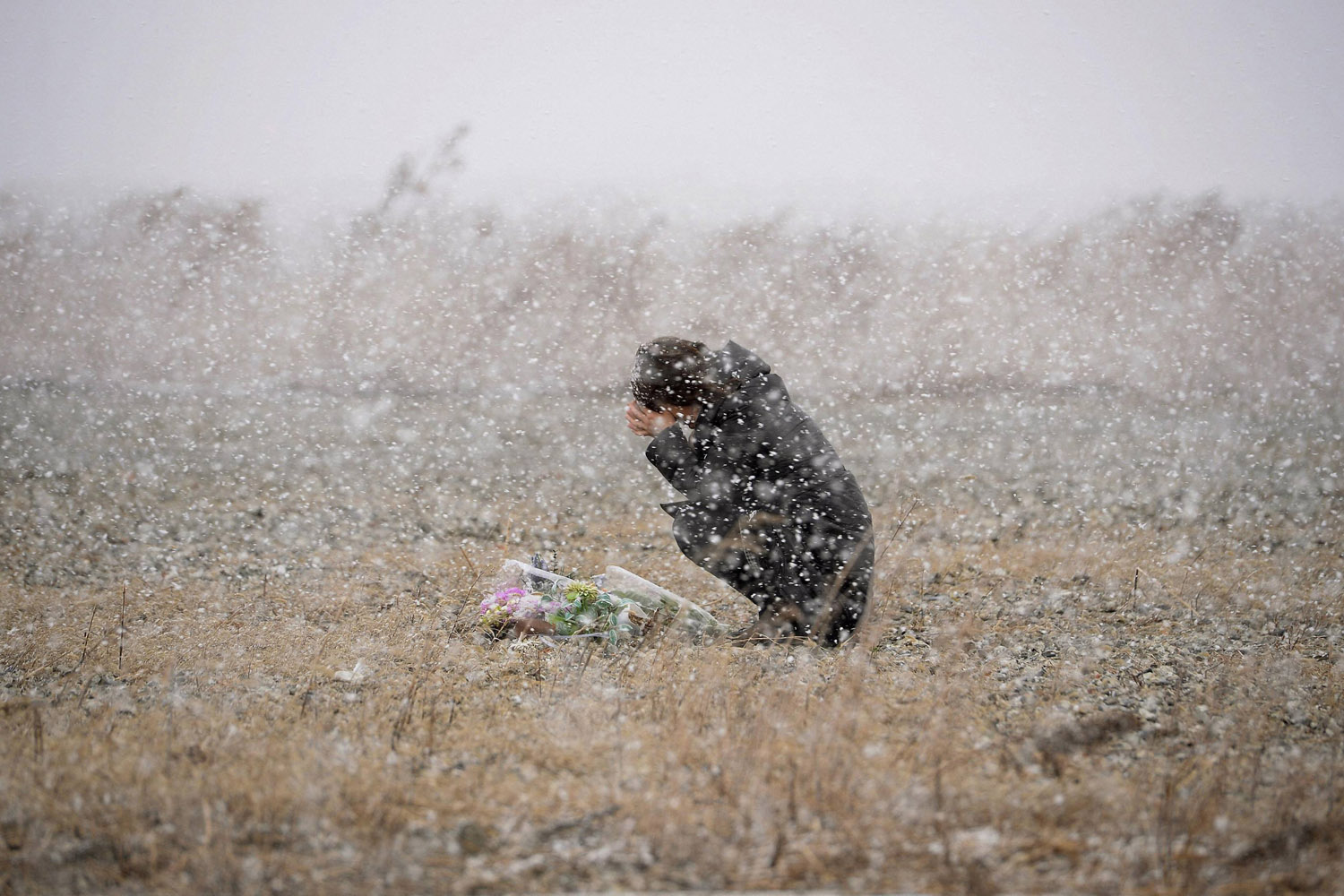 A woman prays for the deceased of March 11, 2011 earthquake and tsunami at a place where she was employed at a photo studio at the time, in Rikuzentakata, Iwate prefecture
