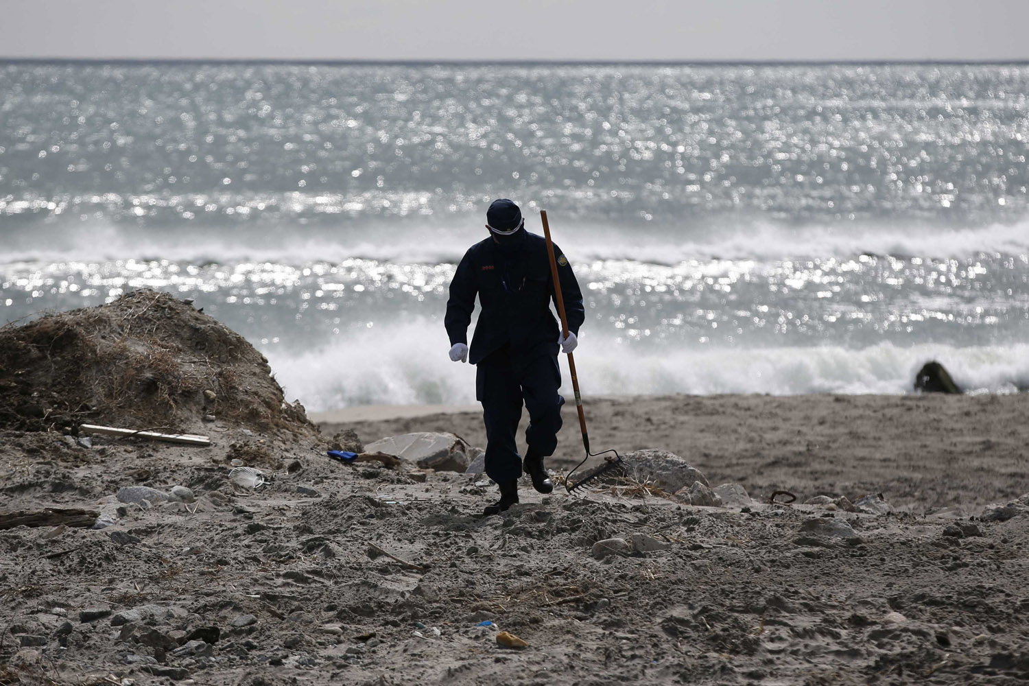 A police officer searches for missing people of the March 11, 2011 earthquake and tsunami along the coast side in Namie town, Fukushima prefectur