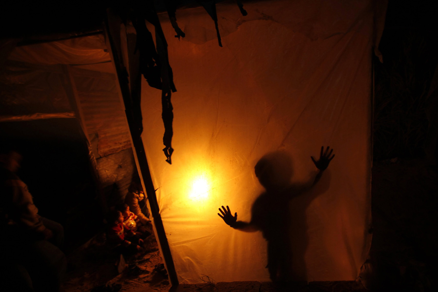 A Palestinian family sits inside their makeshift house during power cuts in Khan Younis in Gaza Strip