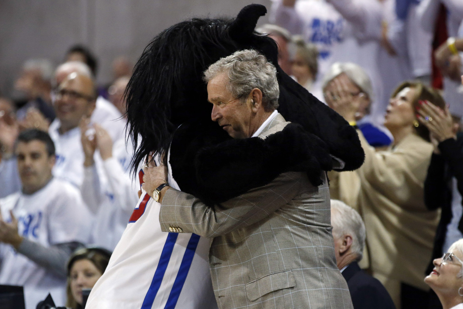 Mar. 5, 2014. Former President George W. Bush gets a hug from SMU mascot Peruna during a break in the first of an NCAA college basketball game between SMU and Louisville.