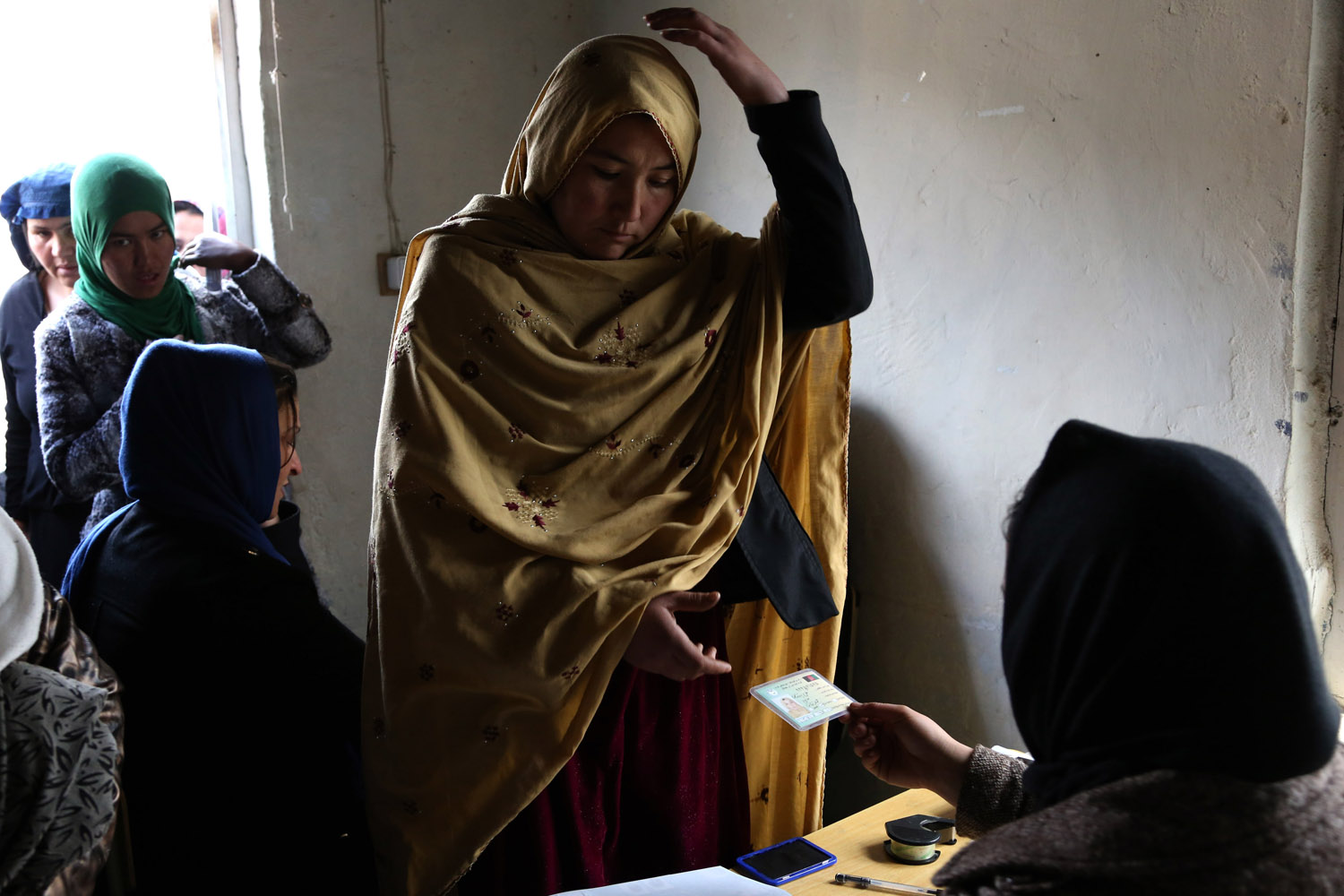 Mar. 17, 2014. An Afghan woman receives her voter registration card from an employee of the Afghan Independent Election Commission at a women's voter registration center in Kabul, Afghanistan.