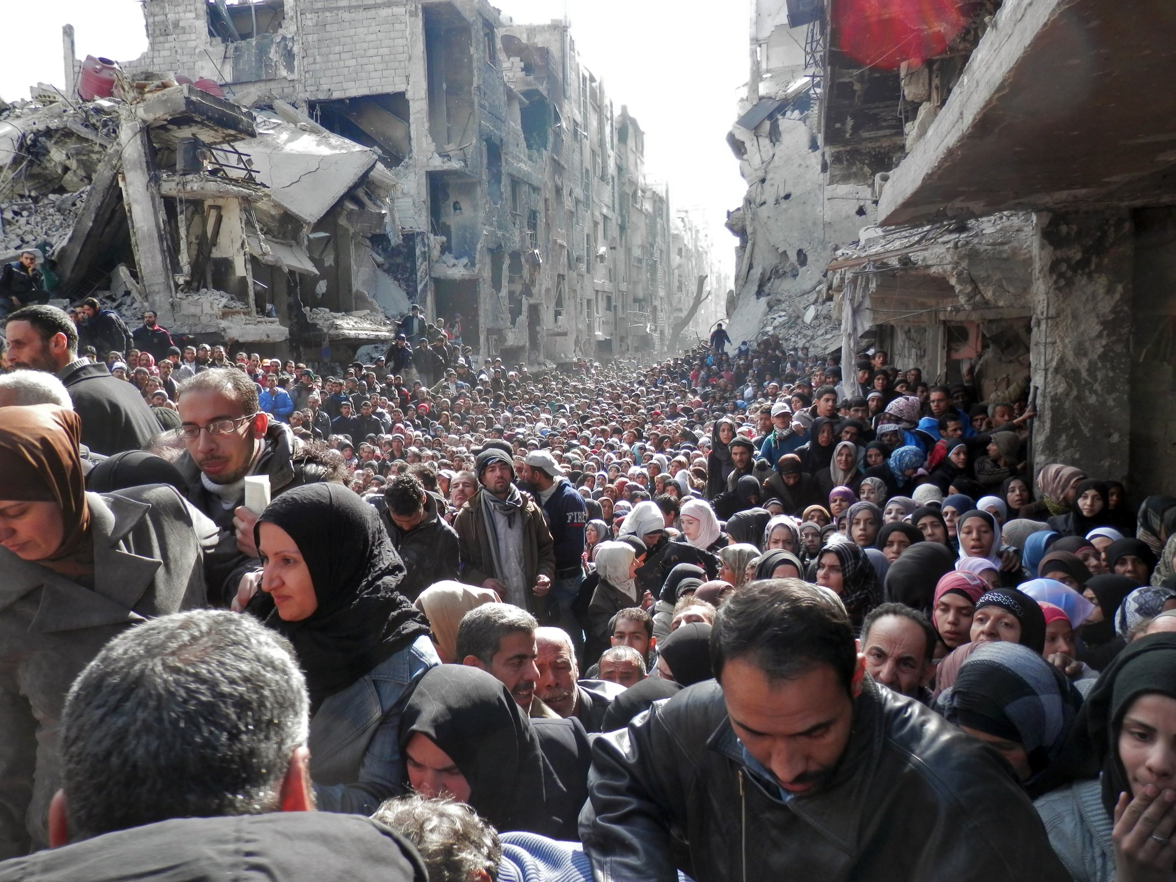 Residents wait in line to receive food aid distributed in the Yarmouk refugee camp on Jan. 31, 2014 in Damascus.