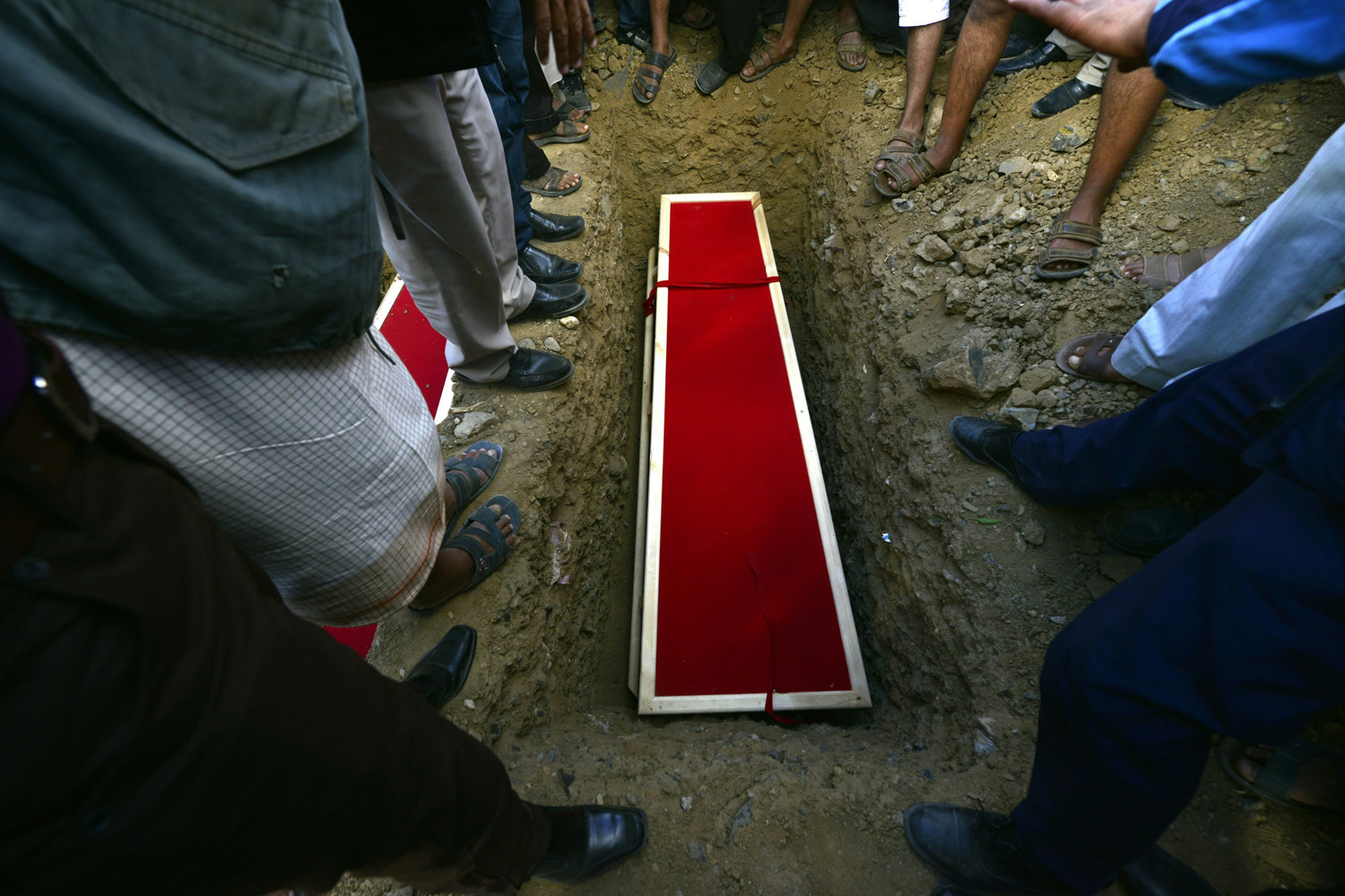 Mar. 30, 2014. Yemeni mourners stand over a grave at a cemetery ahead of burying one of the soldiers who were killed by gunmen at a checkpoint a week ago during a funeral procession in Sanaía, Yemen.