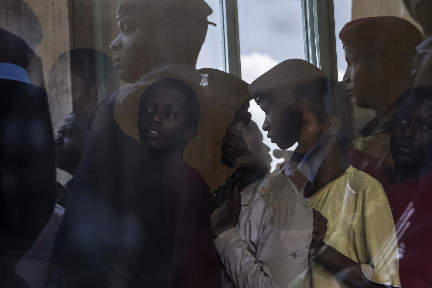 Apr. 9, 2014. Detained Somali men are lined up as police officers are reflected in a window at the Kasarani stadium in Nairobi, Kenya, More than 1,000 Somalis are being held by Kenyan police in a soccer stadium, according to reports. The refugees were arrested in a week-long sweep through Nairobi's Eastleigh neighborhood.