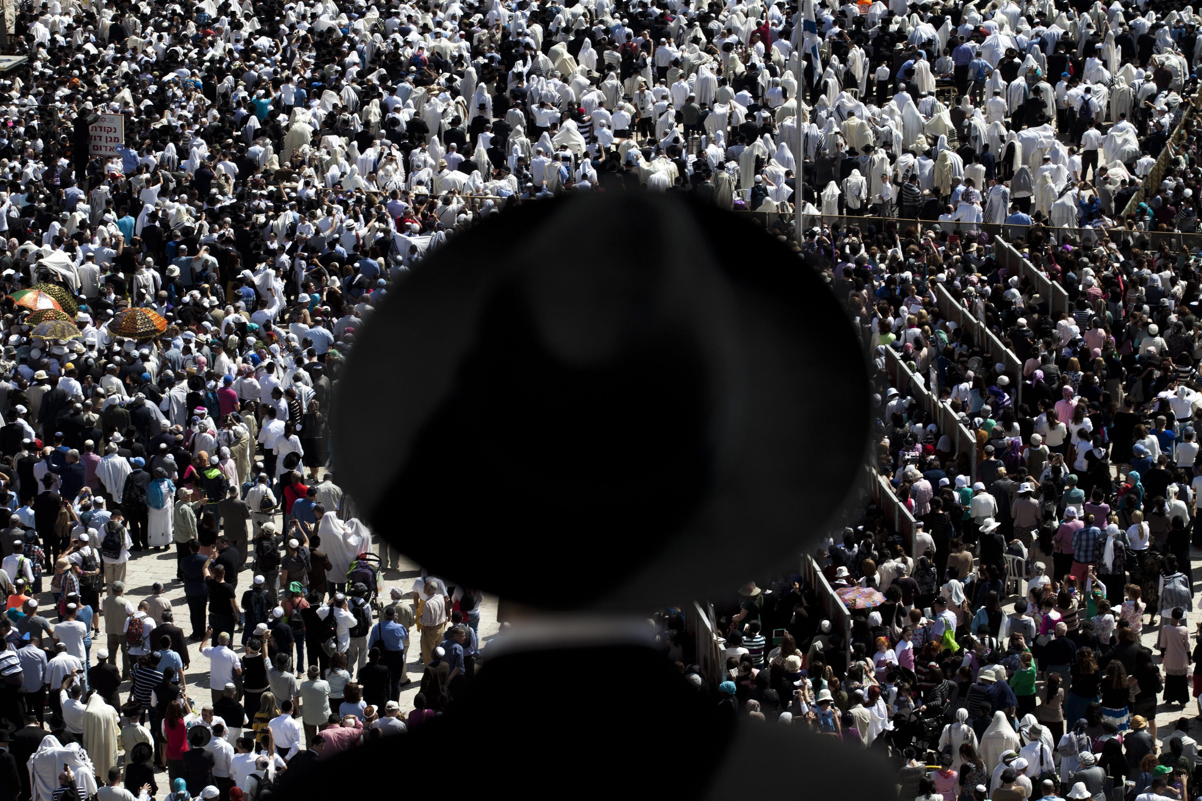 Apr. 17, 2014. An Ultra-Orthodox Jew watches others covering their heads with prayer shawls as they recite the Priestly Blessing during the high holiday of Passover, in front of the Western Wall, Judaism's holiest site, in Jerusalem, Israel.