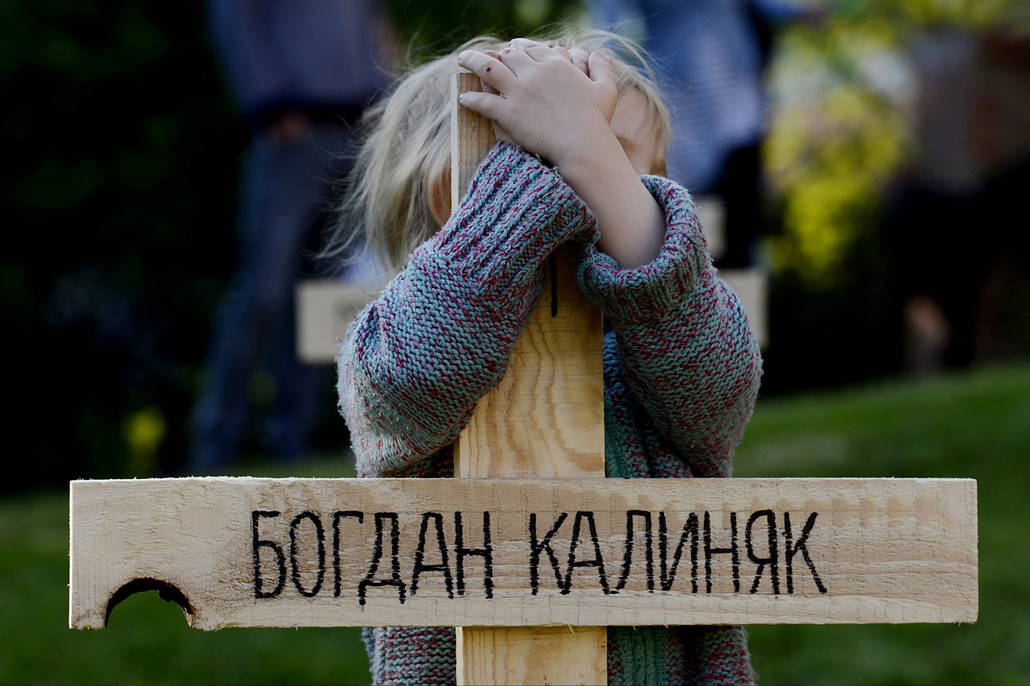 Apr. 23, 2014.  A child hugs one of the 107 crosses that were set up at a symbolical graveyard commemorating the people who died during the recent protest on Kiev's Independent Square, in Prague, Czech Republic.