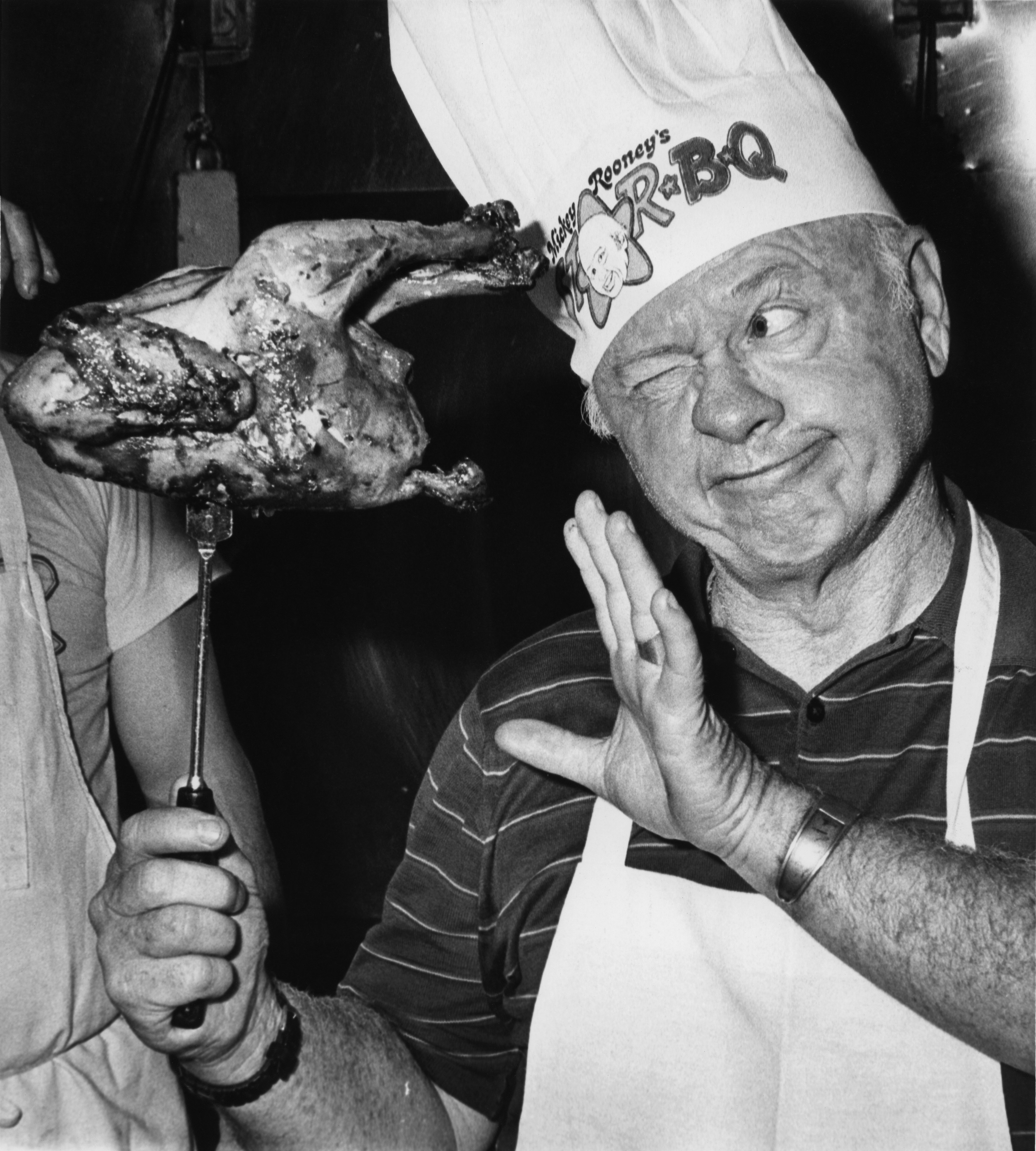 Rooney sizes up a barbecued chicken during festivities at the opening of his 'Mickey Rooney's Star-B-Q' restaurant in Hollywood on April 13 1980 in Los Angeles, California.