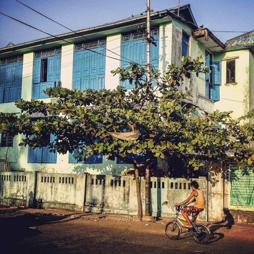 A young Burmese boy rides his bicycle past a Buddhist monastery in downtown Yangon, Myanmar on March 19, 2014.