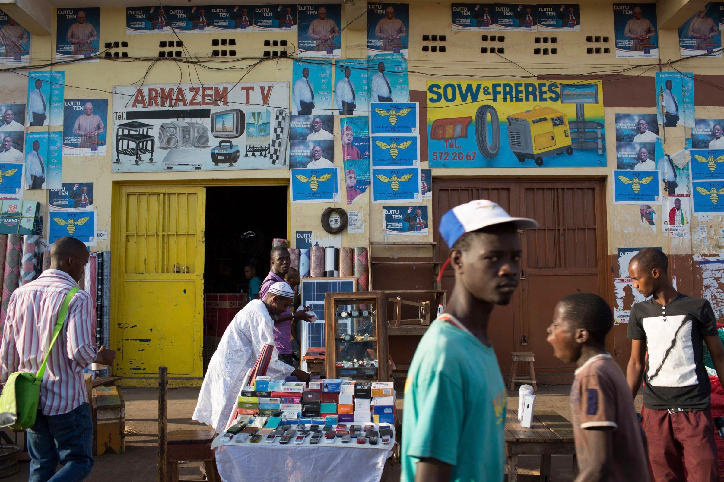 People walk in front of presidential campaign posters in Bissau