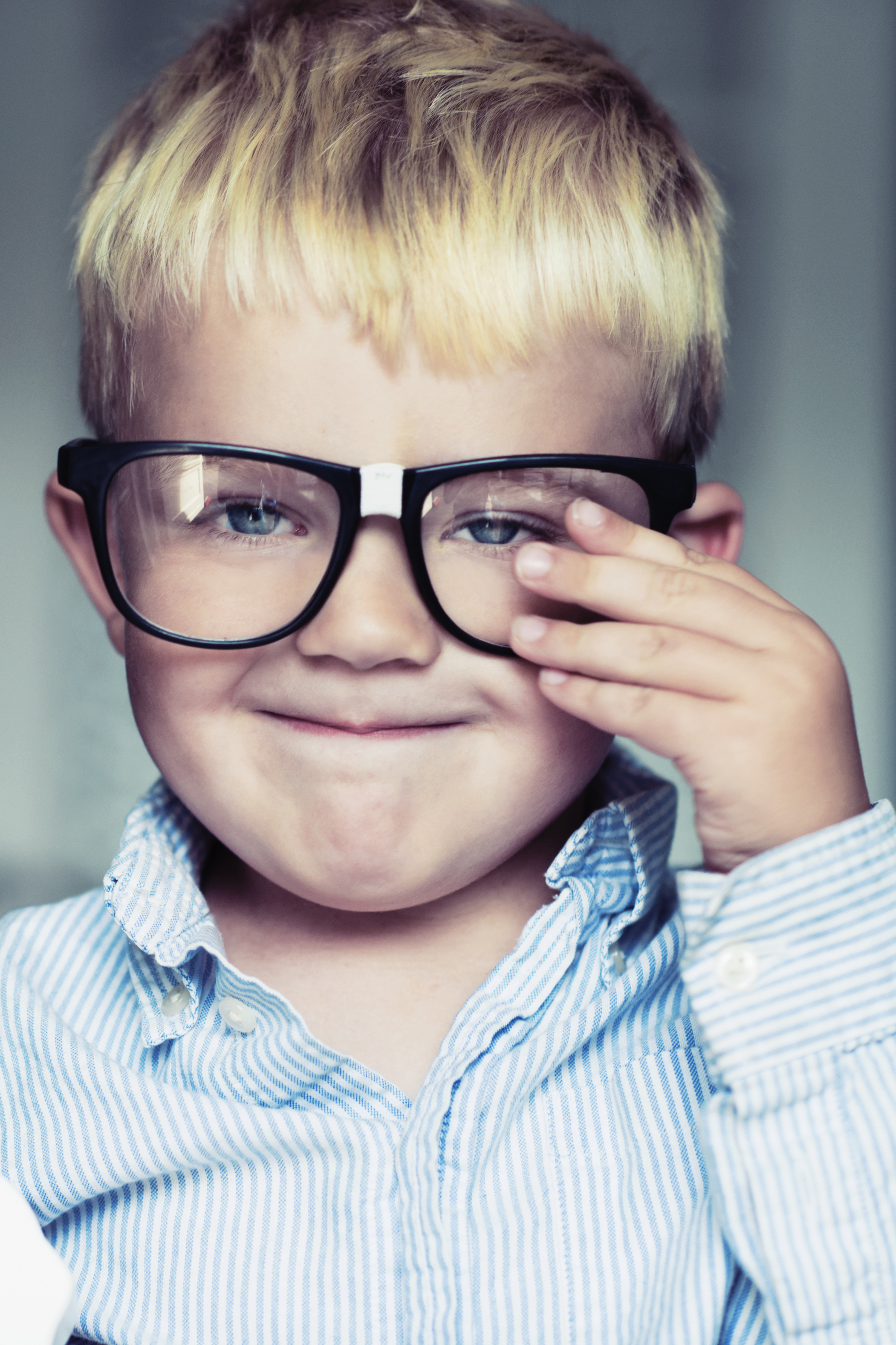 Little boy makes a face while adjusting glasses