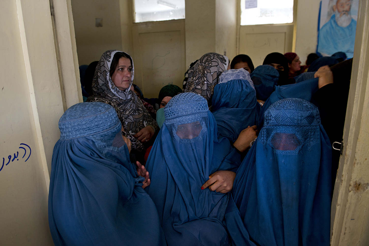Afghans line up to register to vote for Presidential elections at a center run by the Afghan Independent Electoral Commission in Shah Shaheed, Kabul, Afghanistan, March 25, 2014.  There has been a surge in Taliban attacks aimed at derailing elections leading up to voting day in Afghanistan, and the future stability of the country is unclear. (Credit: Lynsey Addario for Time Magazine)