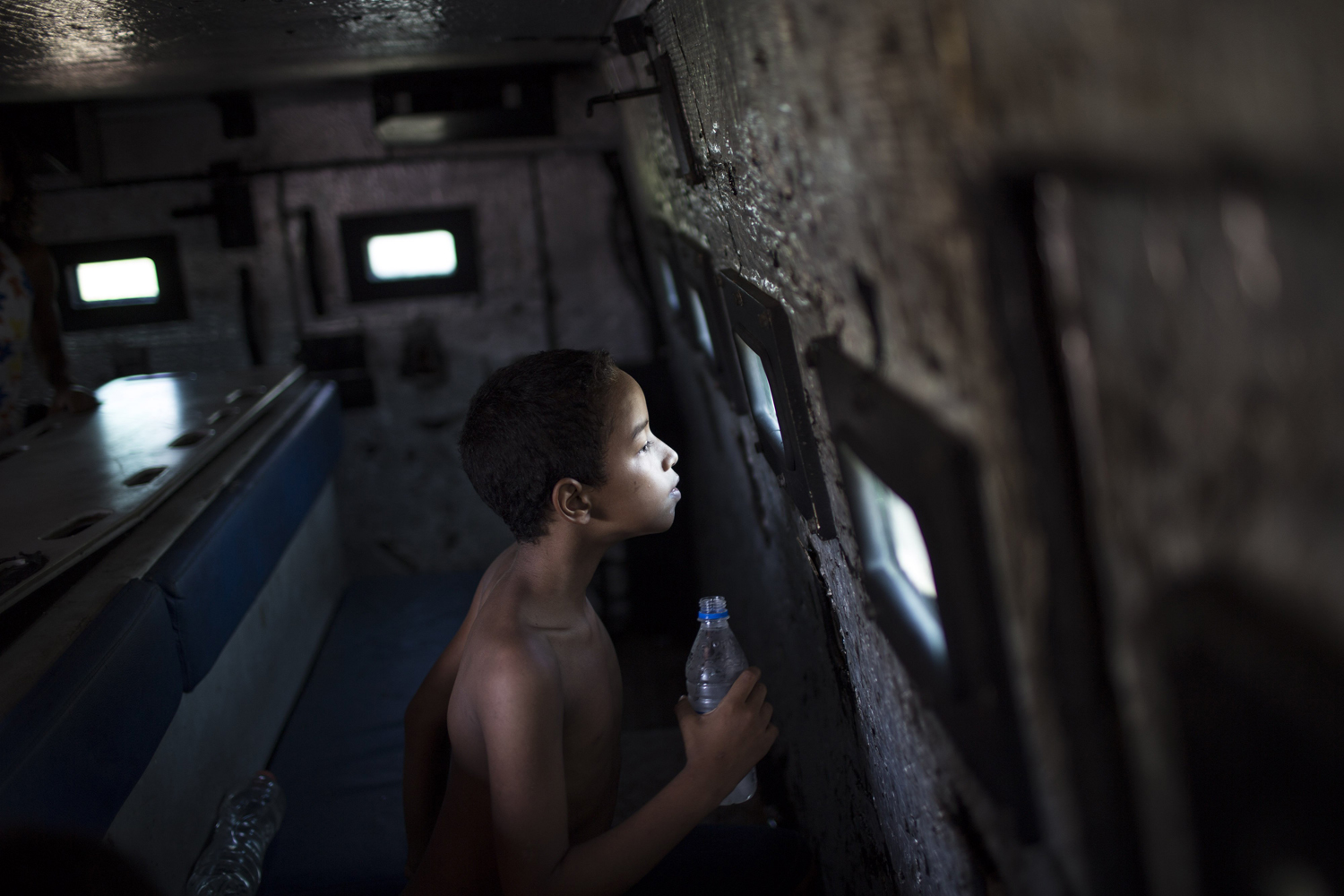 Mar. 30, 2014. A young resident looks through a small bullet proof window as he sits inside a police armored vehicle after a police operation to occupy the Vila Pinheiro, part of the Mare slum complex in Rio de Janeiro, Brazil.