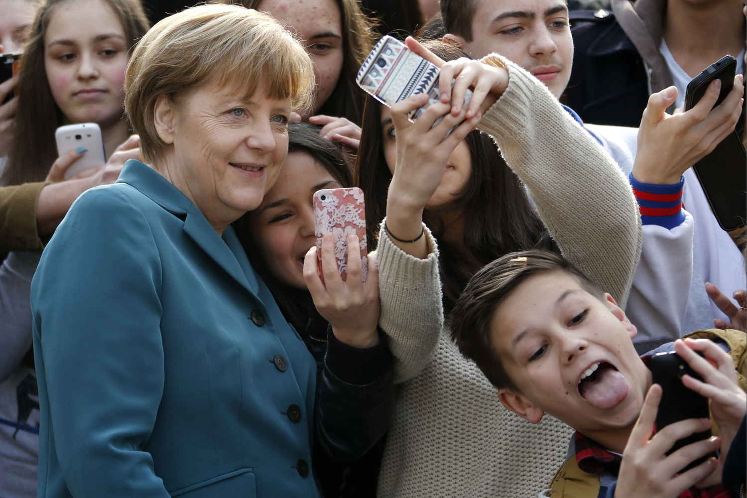 Students take 'selfies' with German Chancellor Angela Merkel as she arrives for a visit at Robert-Jungk Europe high school as part of the Europe-Project Day, in Berlin March 31, 2014 .