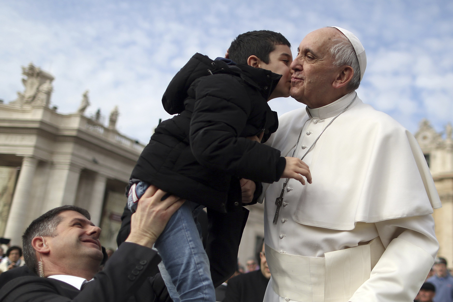 Pope Francis kisses child as he arrives to lead his Wednesday general audience in Saint Peter's Square at the Vatican